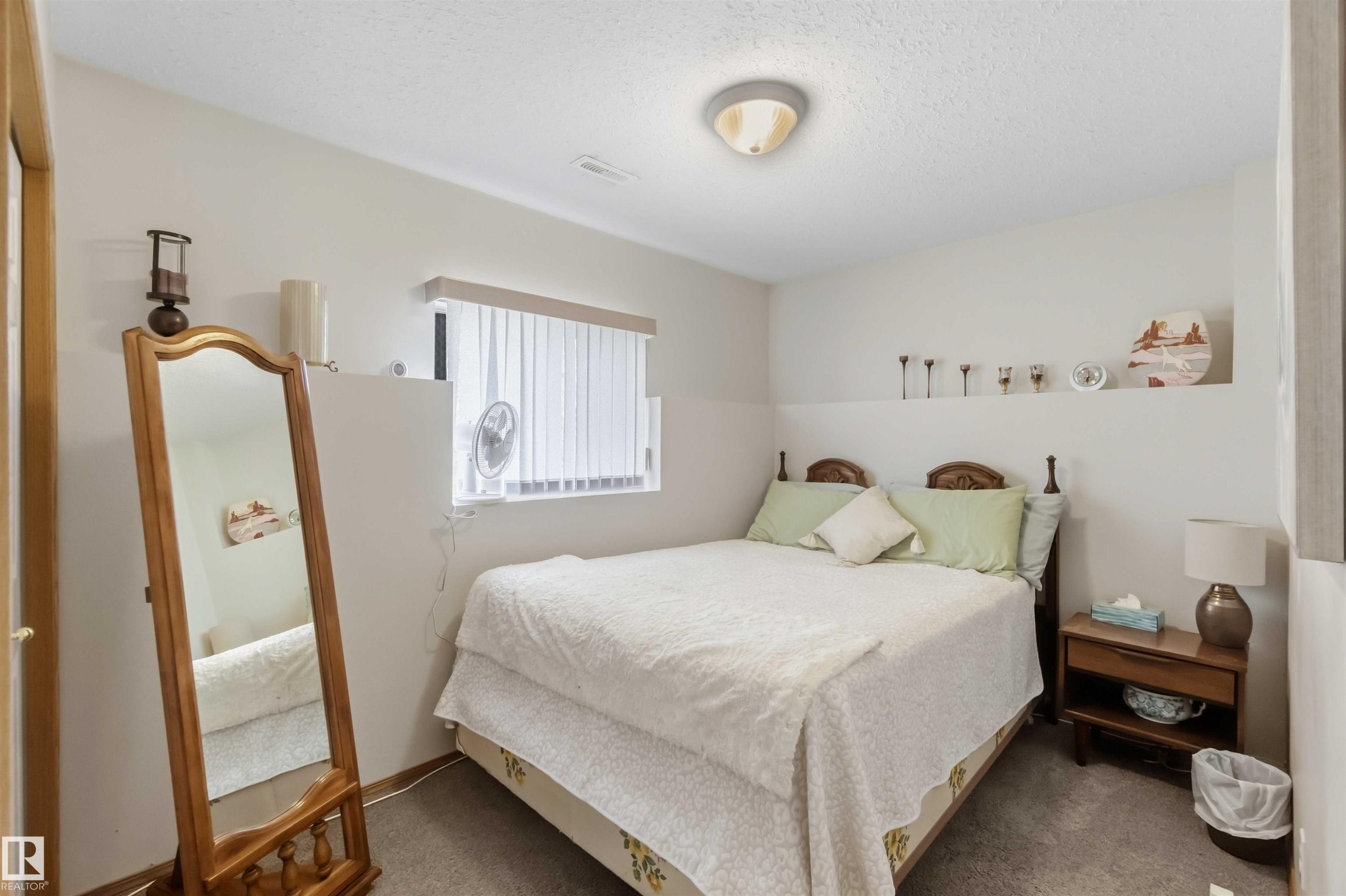 Virtually Decluttered- Bathroom featuring a wooden vanity, integrated countertop with a white oval sink, wall-mounted mirror, and multi-bulb light fixture - 497 Kananaskis Drive, Devon, AB