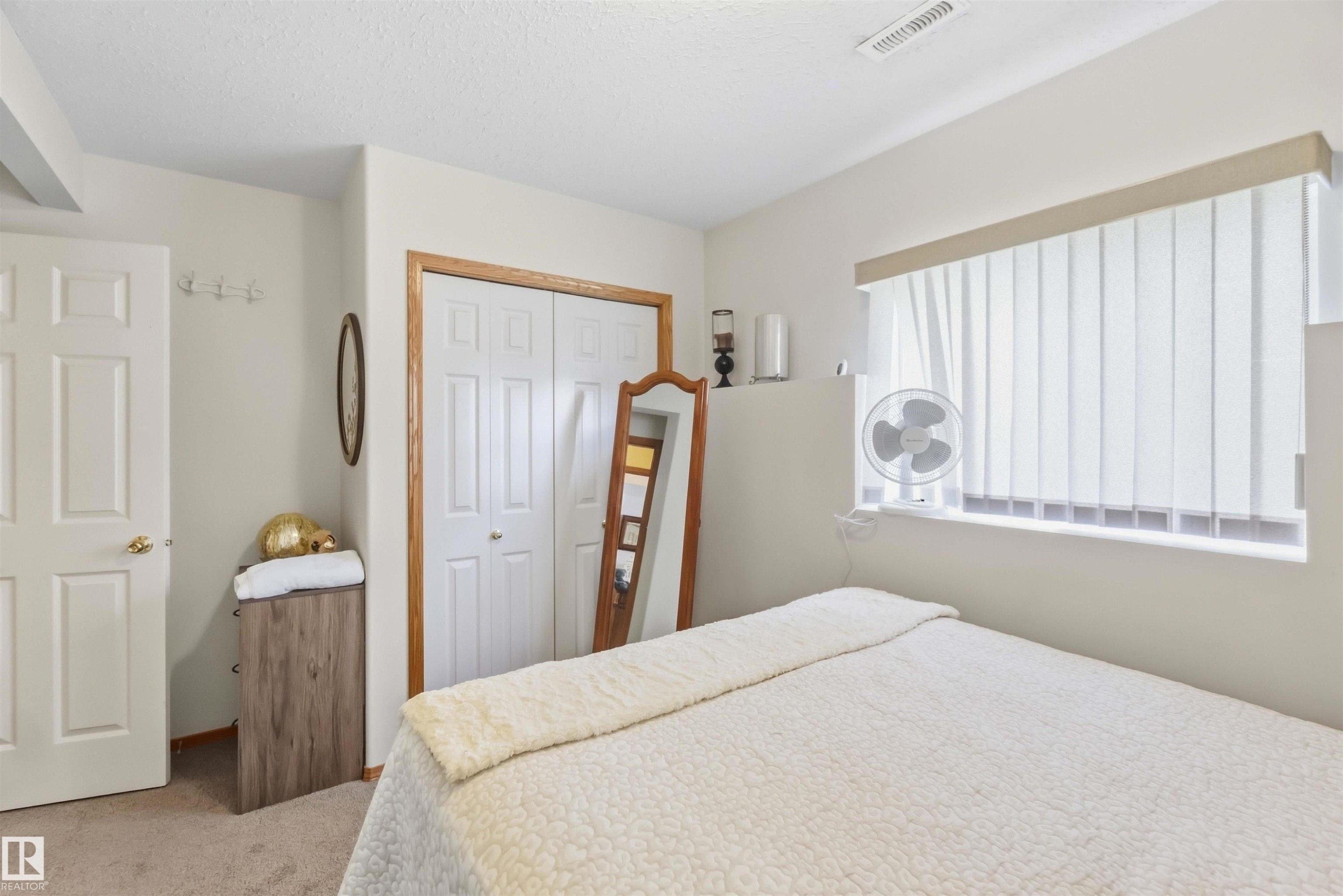 Virtually Decluttered- Full-width vanity mirror, integrated sink countertop, wood cabinetry, and a white acrylic tub-shower combination - 497 Kananaskis Drive, Devon, AB