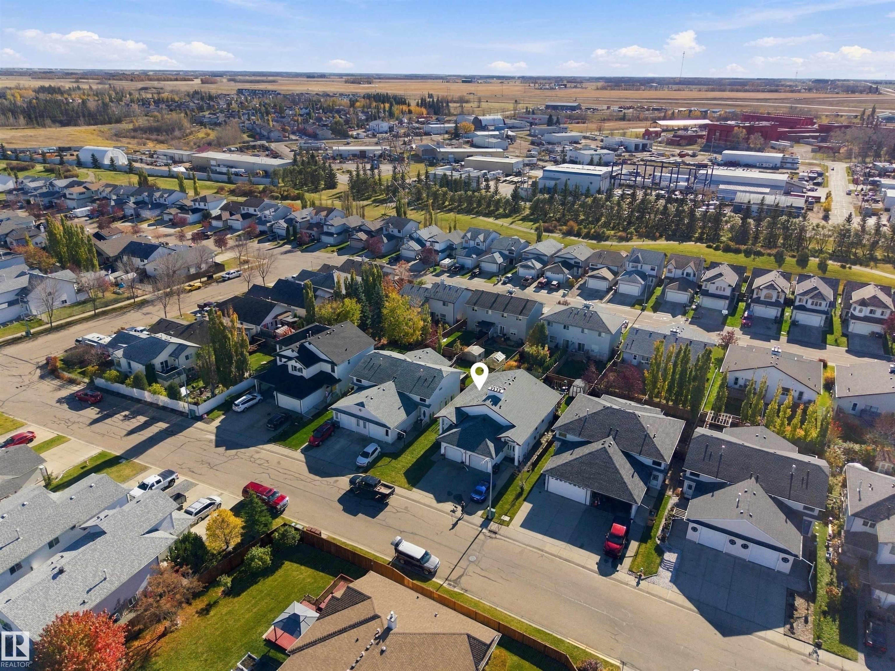 Bi-level exterior featuring light horizontal siding, dual-car garage, concrete driveway, and side chain-link fencing - 497 Kananaskis Drive, Devon, AB