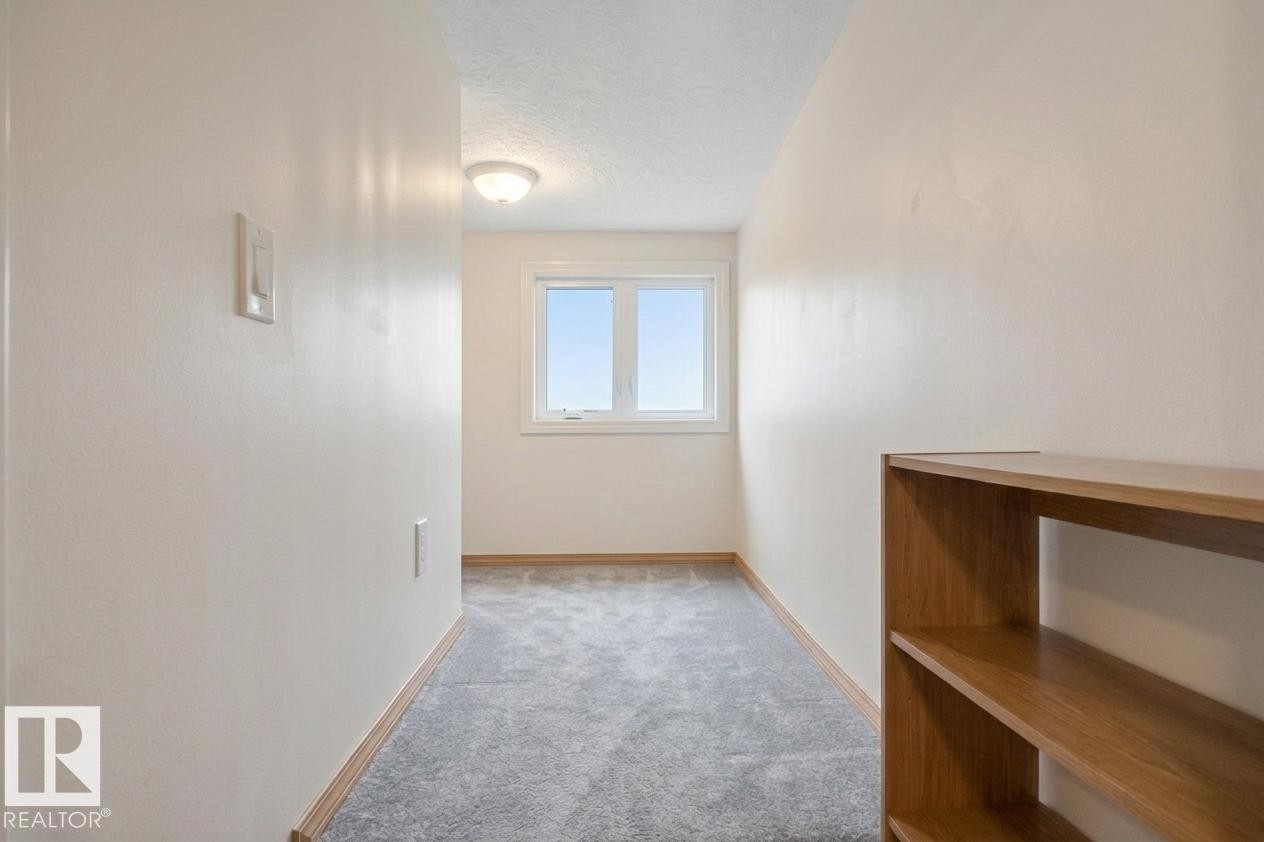 Entryway featuring a front door with two vertical textured glass panels, a matching glass sidelight, bi-fold closet doors, and wood-finish door trim - 497 Kananaskis Drive, Devon, AB