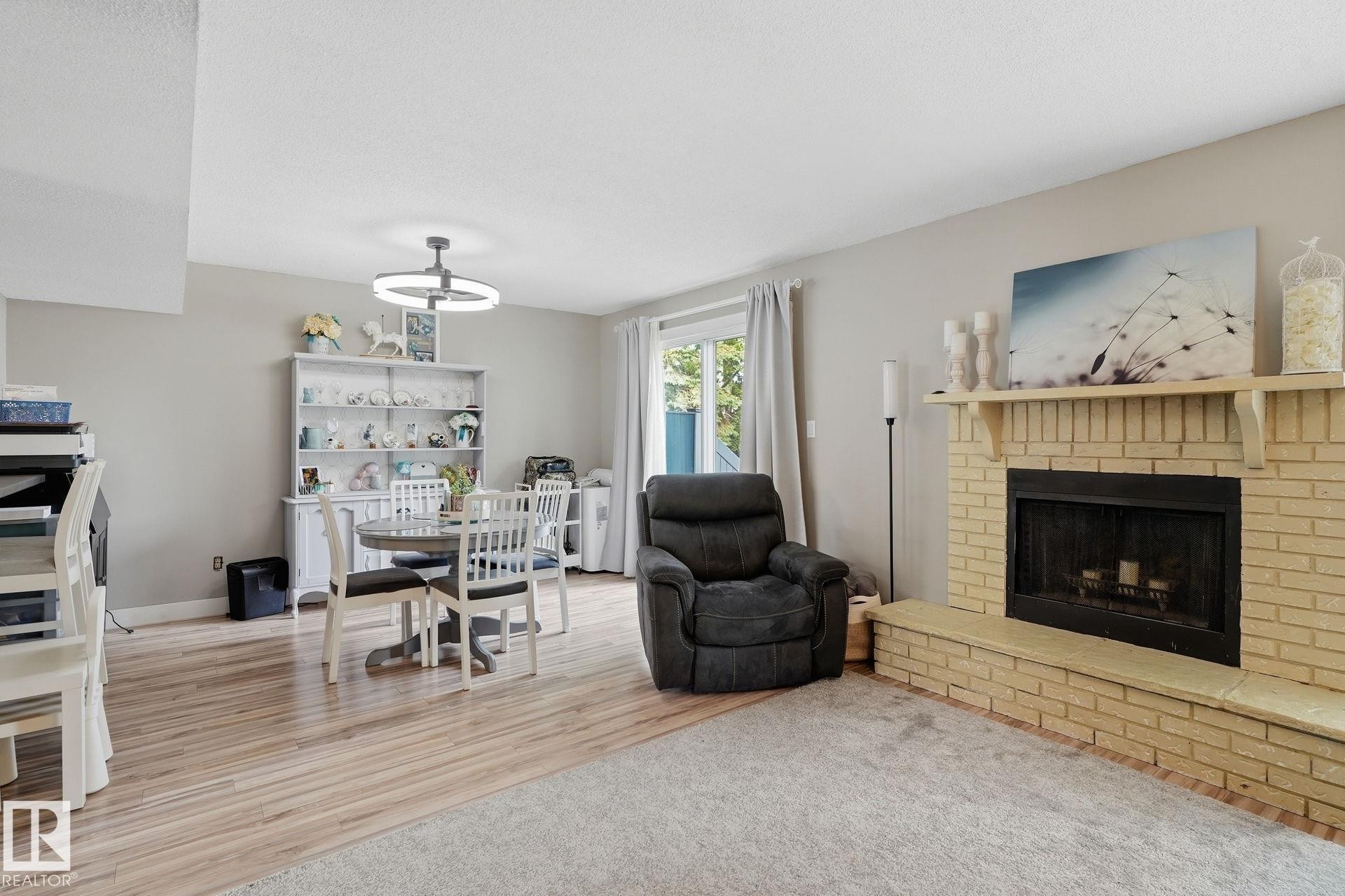 Brick fireplace with hearth, wood-finish flooring, sliding glass door, and recessed lighting - 5340 38A Avenue Nw, Edmonton, AB