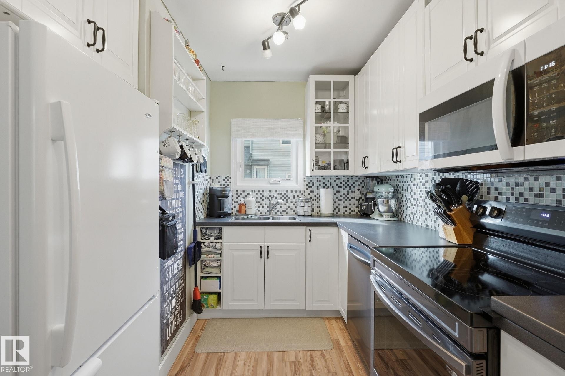 White cabinetry with black hardware, mosaic tile backsplash, wood-finish flooring, recessed lighting, and built-in microwave - 5340 38A Avenue Nw, Edmonton, AB