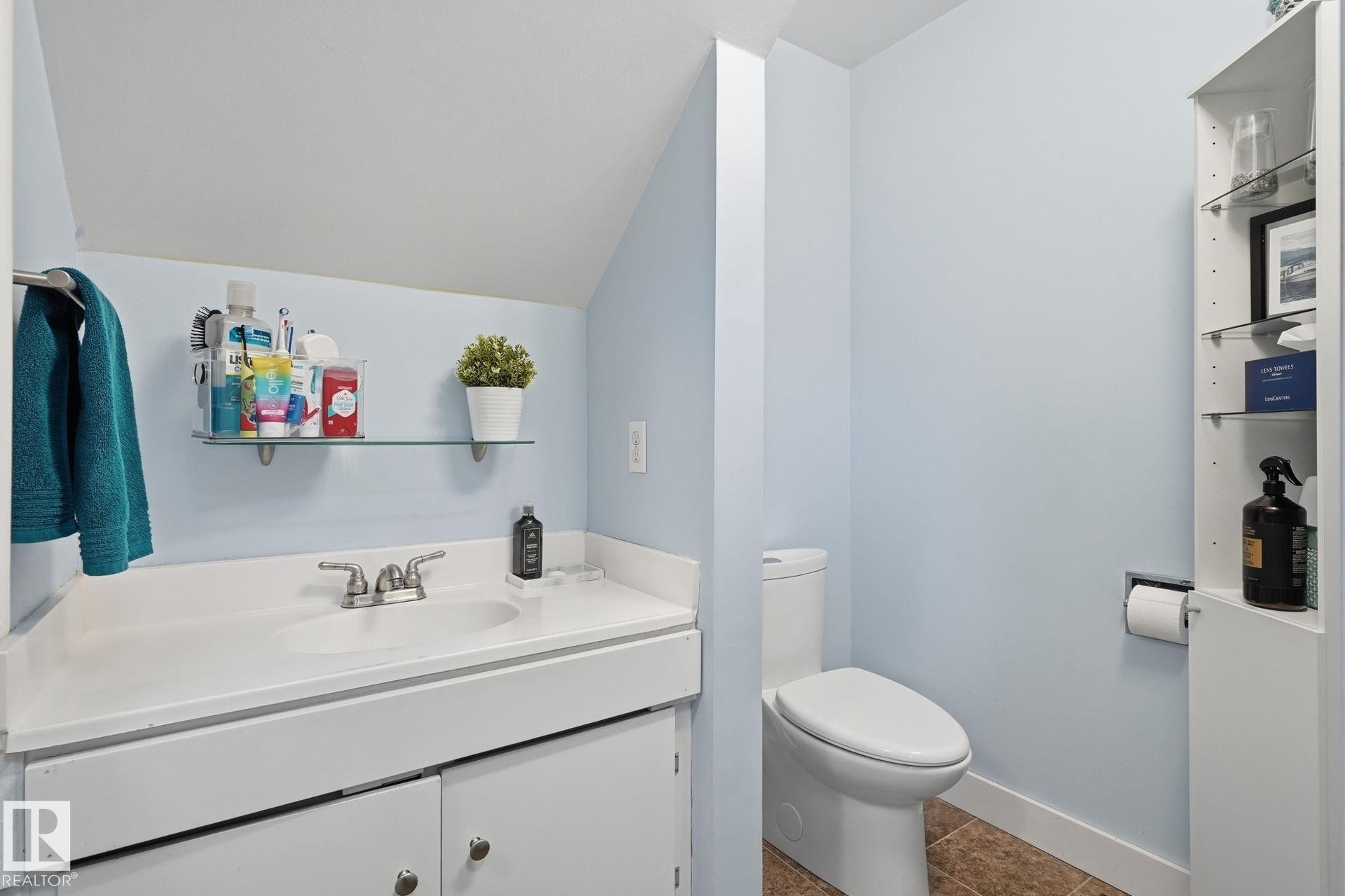 White vanity with an integrated sink and chrome faucet, glass shelf, and a built-in vertical storage cabinet - 5340 38A Avenue Nw, Edmonton, AB