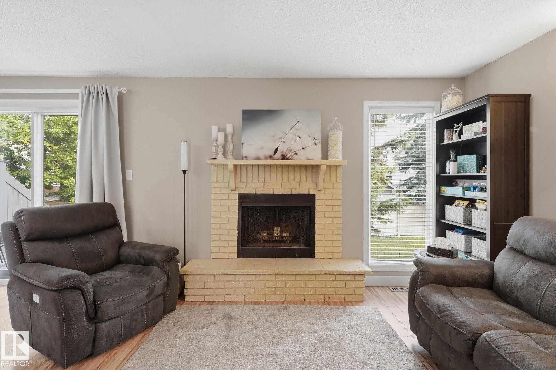 Brick fireplace with hearth, wood-finish flooring, glass sliding door, and a built-in bookcase - 5340 38A Avenue Nw, Edmonton, AB
