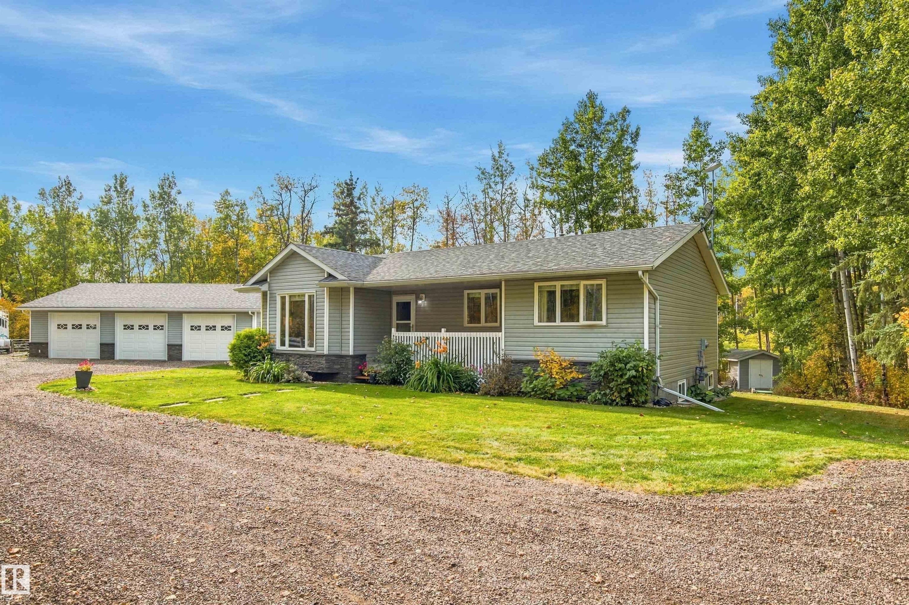 Single-story residence featuring light gray siding, a prominent bay window, and a white railing on the front porch - 51064 Rge Rd 222, Rural Strathcona County, AB
