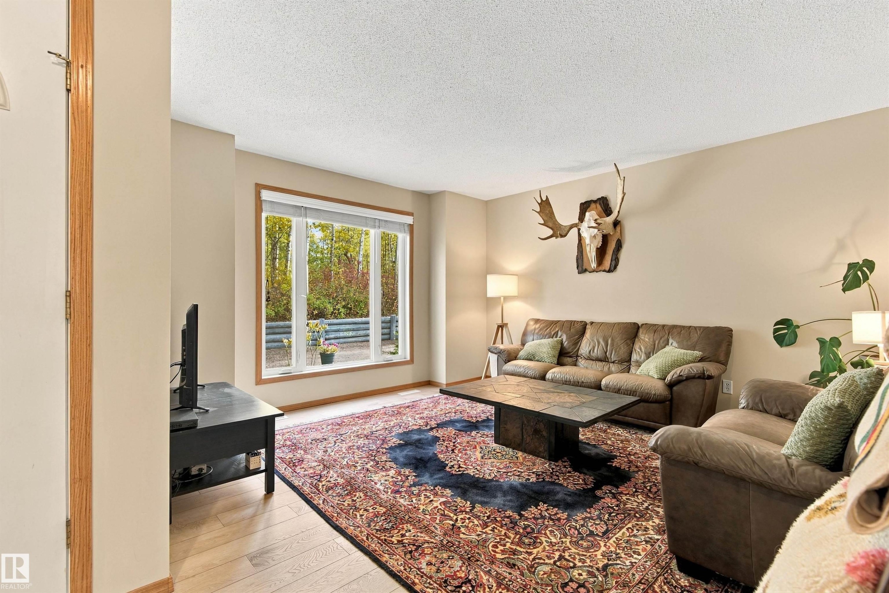 Large windows offering ample natural light, neutral wall colors, and wood-finish flooring - 51064 Rge Rd 222, Rural Strathcona County, AB