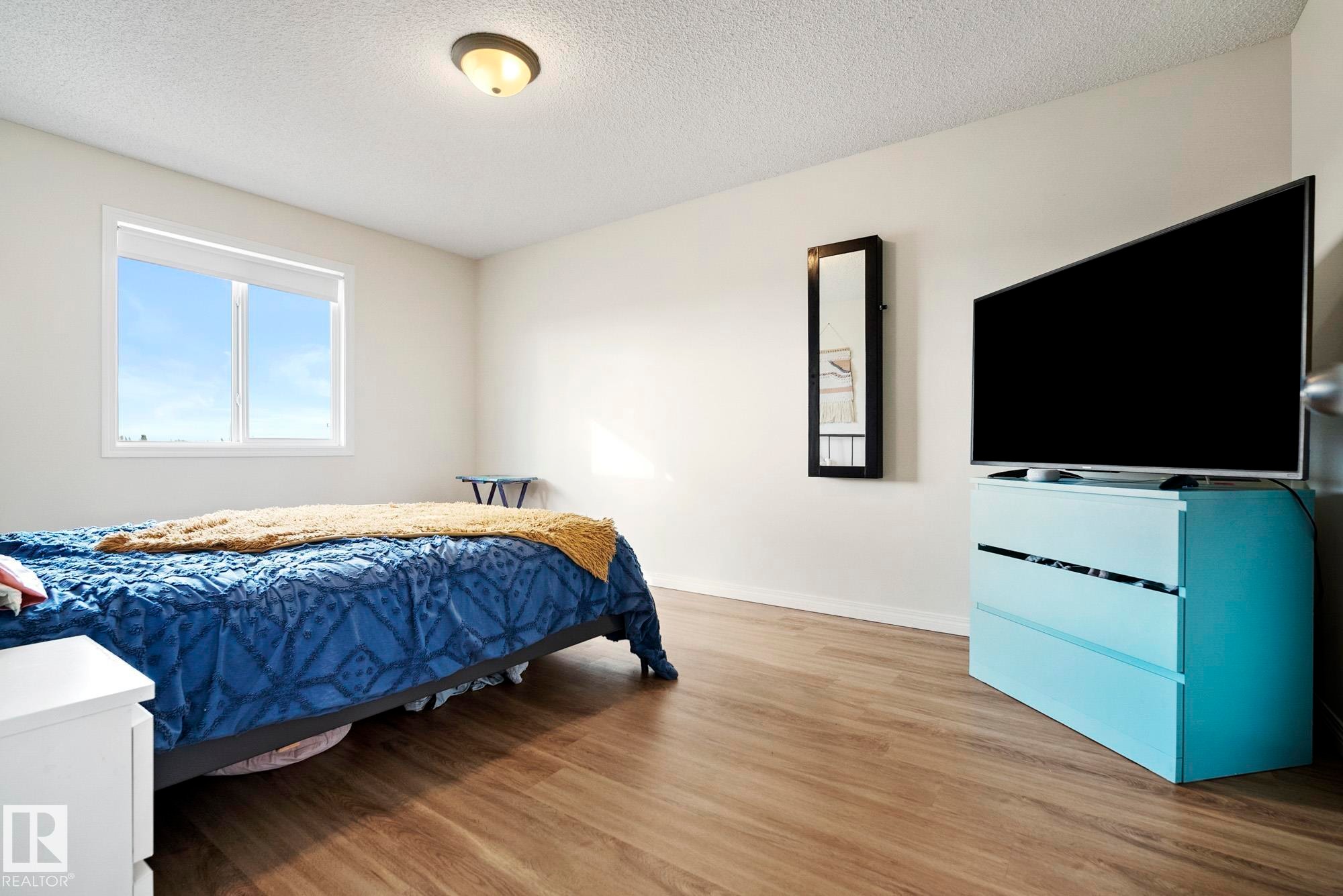Wood-finish flooring, white walls, and a window with a roller shade - #416 111 Edwards Dr Sw, Edmonton, AB