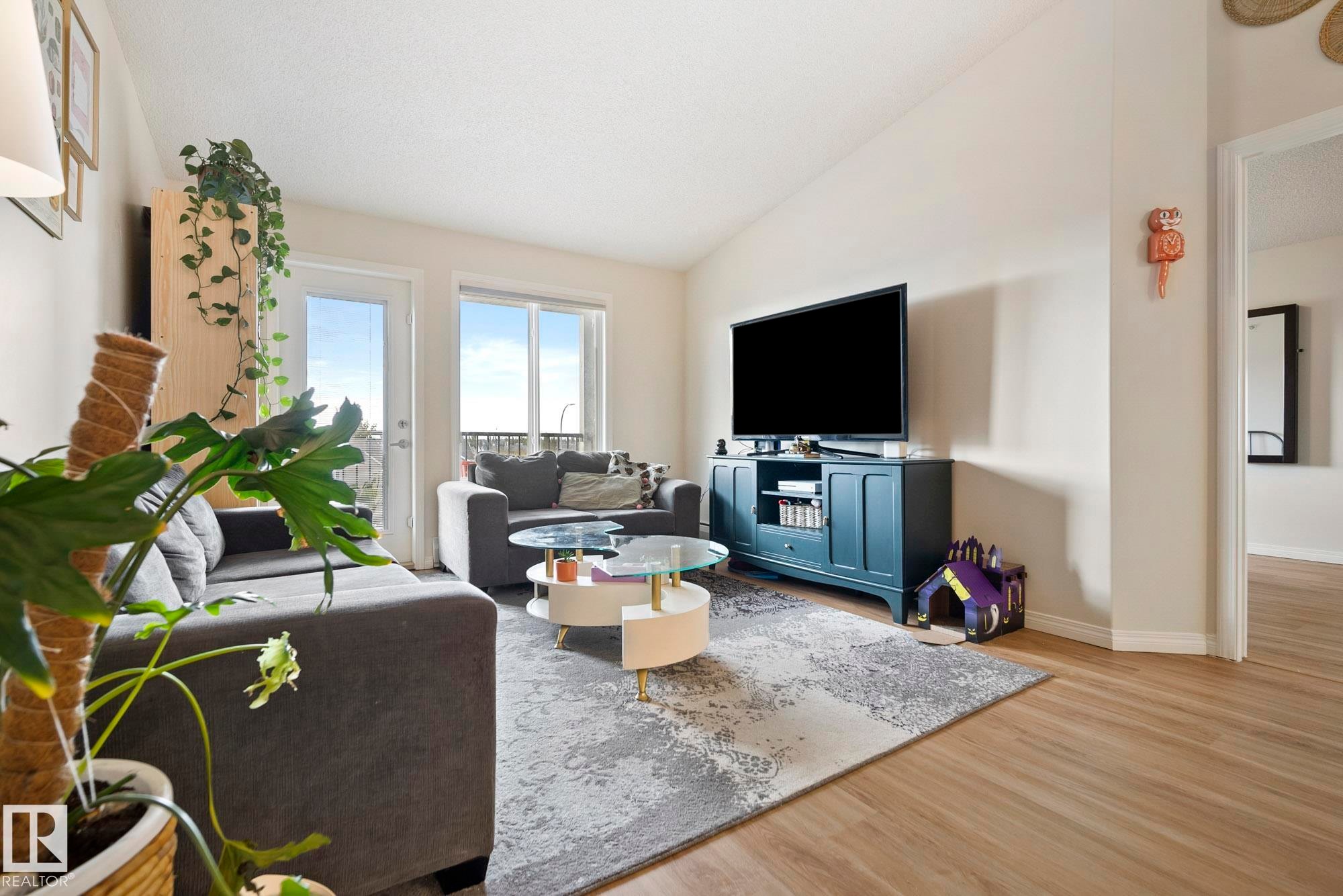Vaulted ceiling, light wood-finish flooring, sliding glass door, and a light color palette throughout - #416 111 Edwards Dr Sw, Edmonton, AB