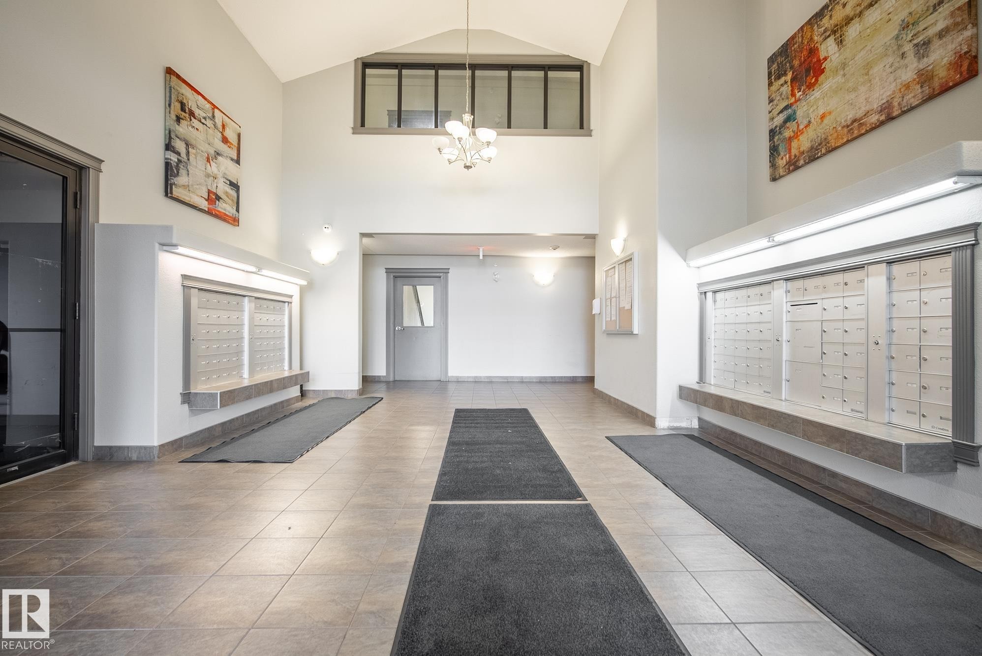 Tiled flooring entrance featuring a vaulted ceiling and integrated mailbox system - #416 111 Edwards Dr Sw, Edmonton, AB
