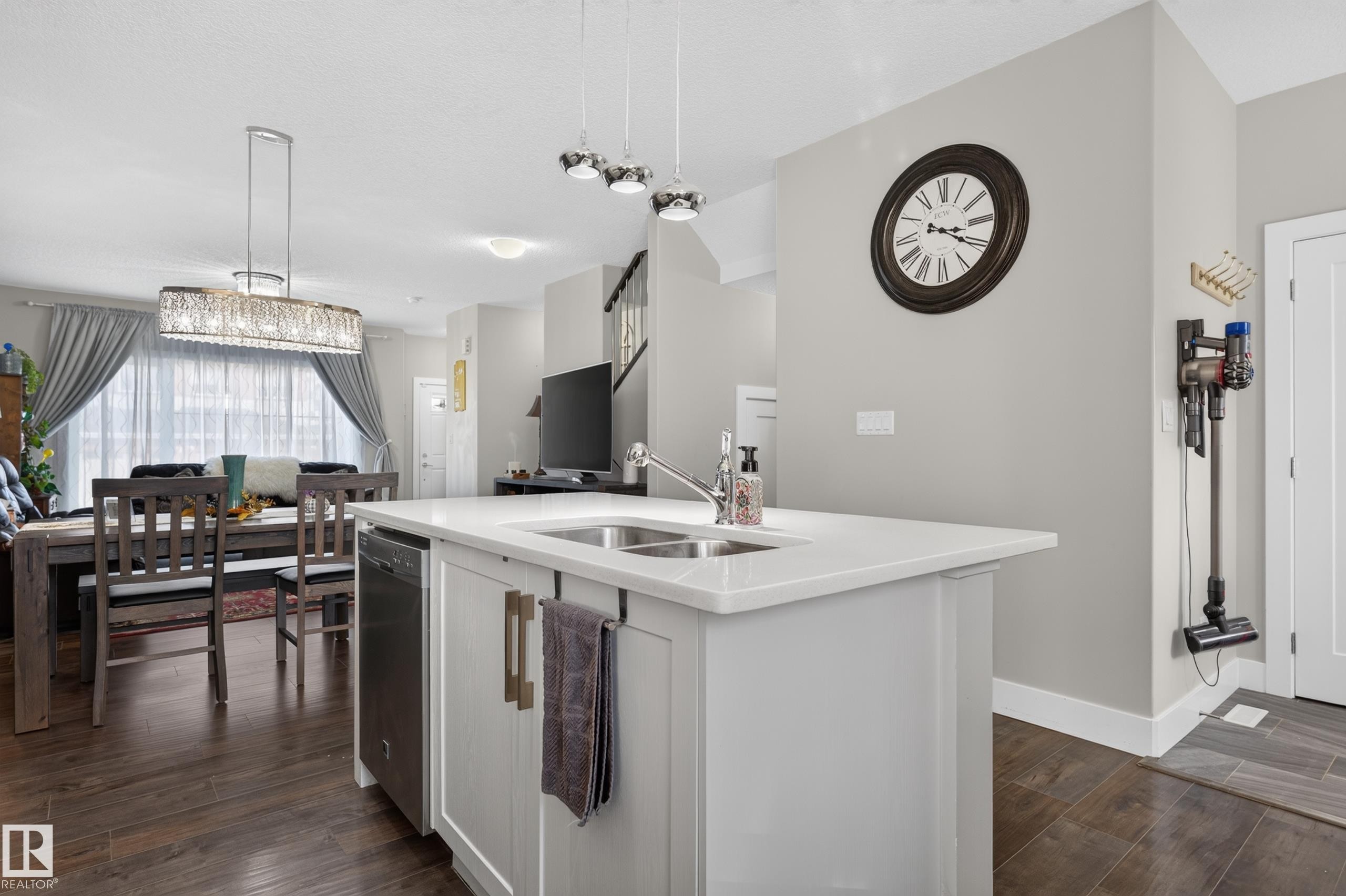 Kitchen island featuring a dual-basin stainless steel sink, solid-surface countertop, and lower cabinetry with metallic hardware - 798 Berg Loop, Leduc, AB