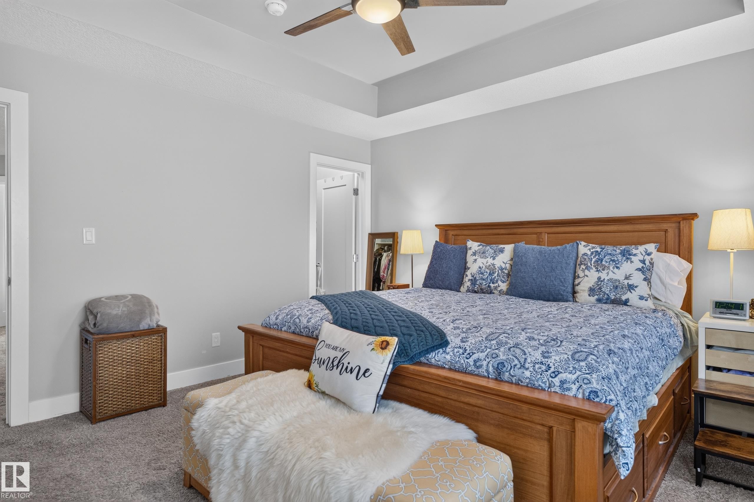 Room featuring a tray ceiling, neutral wall tones, neutral carpeting, and a ceiling fan with integrated lighting - 798 Berg Loop, Leduc, AB
