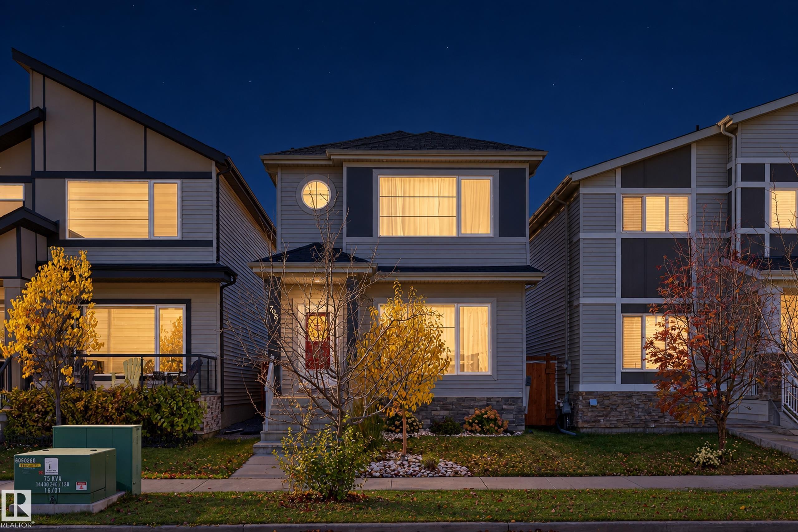 Two-story residence featuring composite siding, stone veneer base, prominent circular accent window, and covered front entry - 798 Berg Loop, Leduc, AB