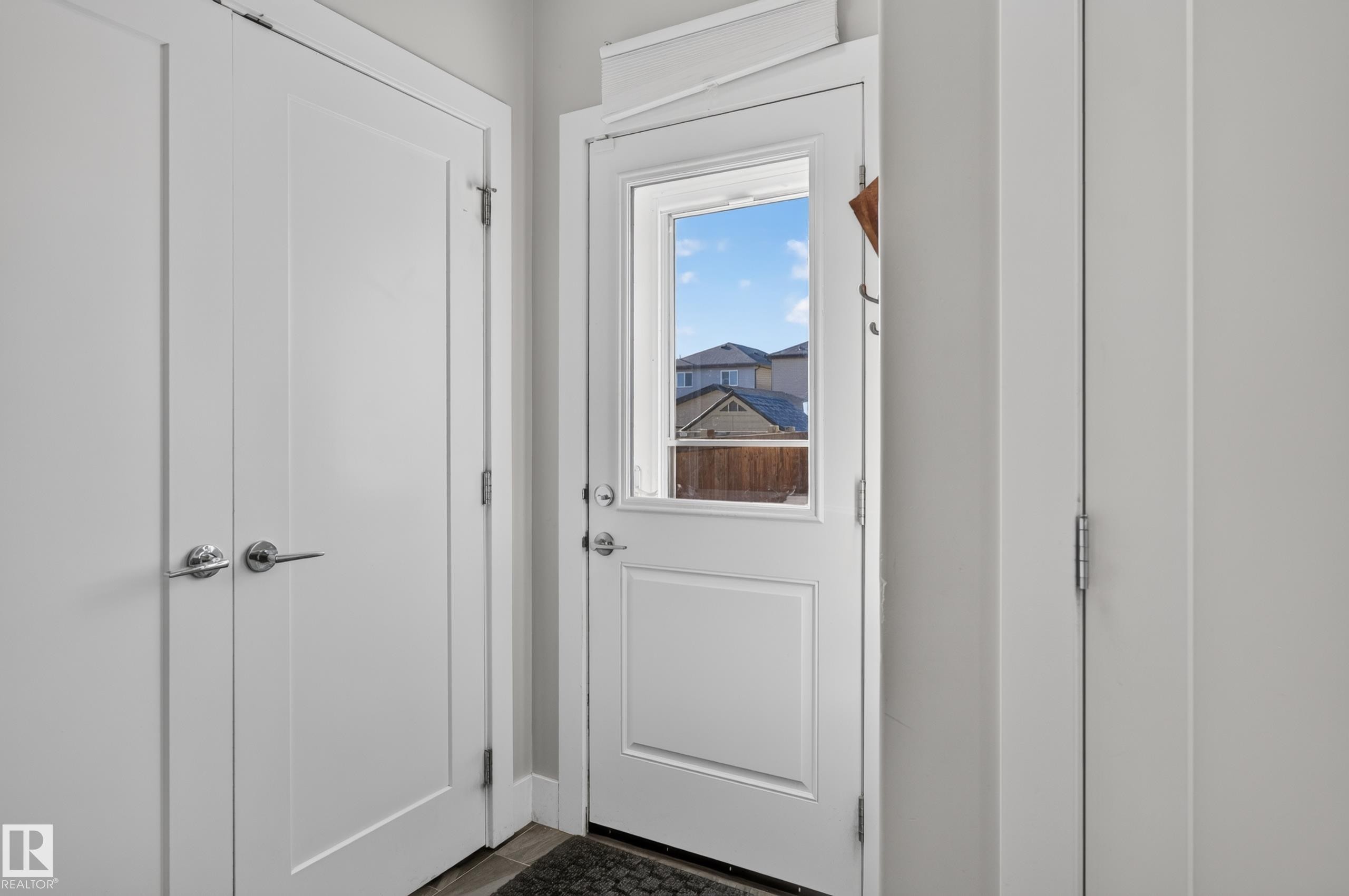 Single-panel exterior door with integrated window and polished chrome hardware, paired with two full-height interior closet doors featuring matching chrome lever handles - 798 Berg Loop, Leduc, AB