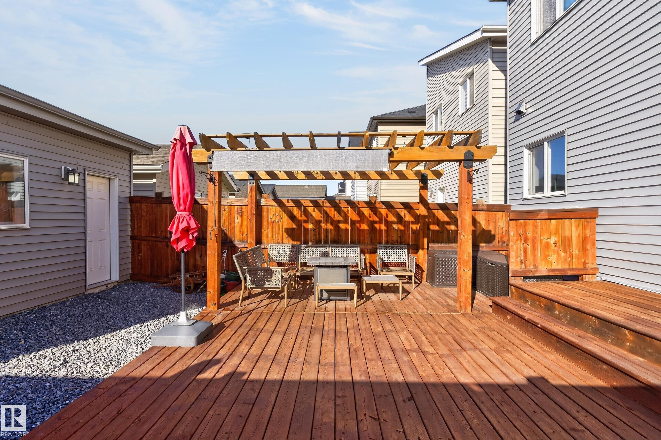 Exterior wood deck featuring a wooden pergola, privacy fencing, and a gravel ground surface - 798 Berg Loop, Leduc, AB
