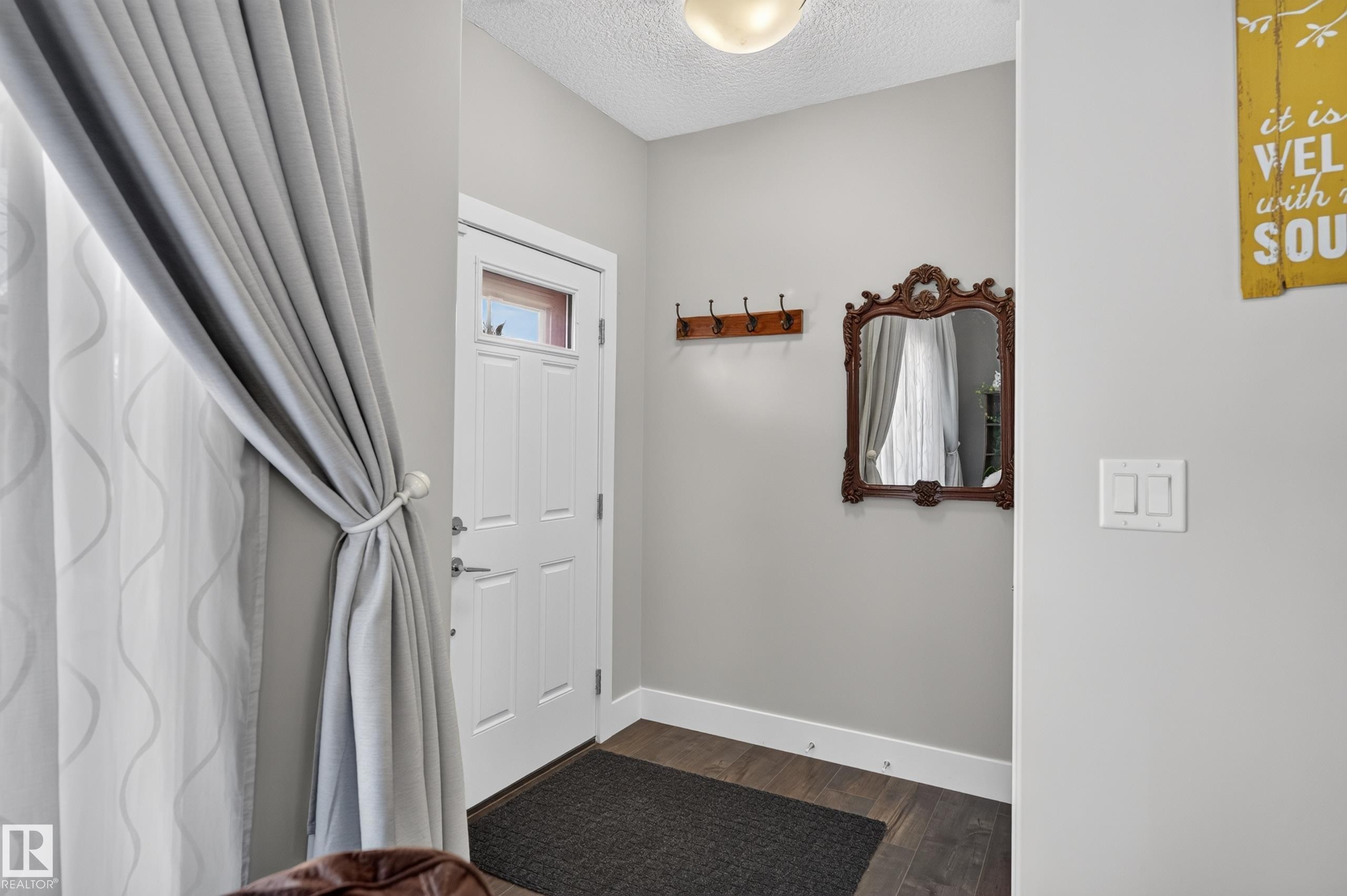 Entryway featuring wood-finish flooring, a white paneled door with a glass insert, and a wall-mounted hook rail - 798 Berg Loop, Leduc, AB