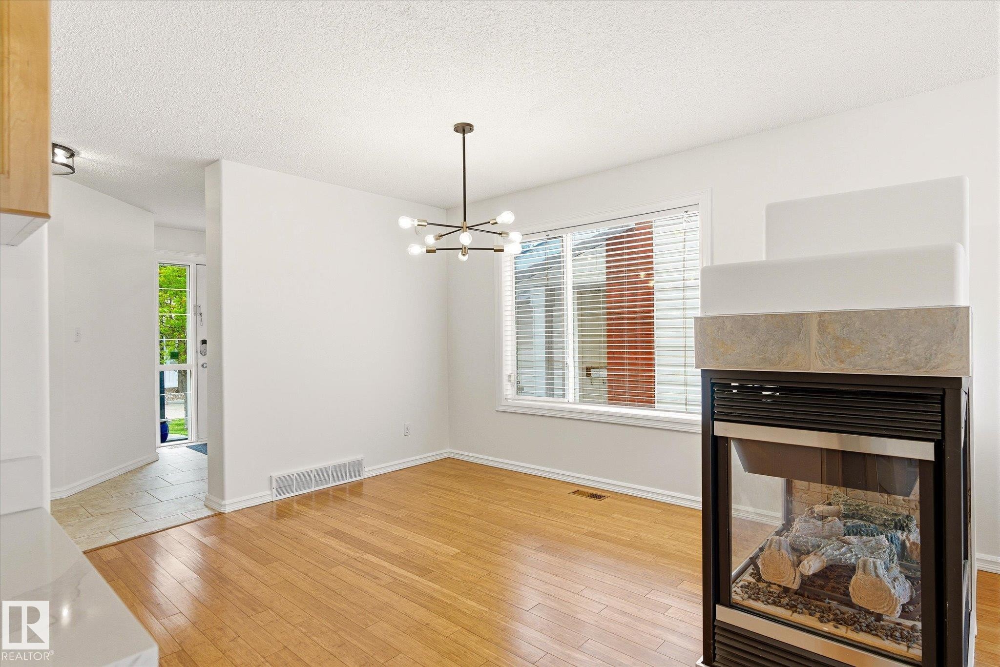 Hardwood-finish flooring, built-in fireplace with stone-finish surround, contemporary chandelier, and large window with blinds - 2550 Rabbit Hill Road Nw, Edmonton, AB