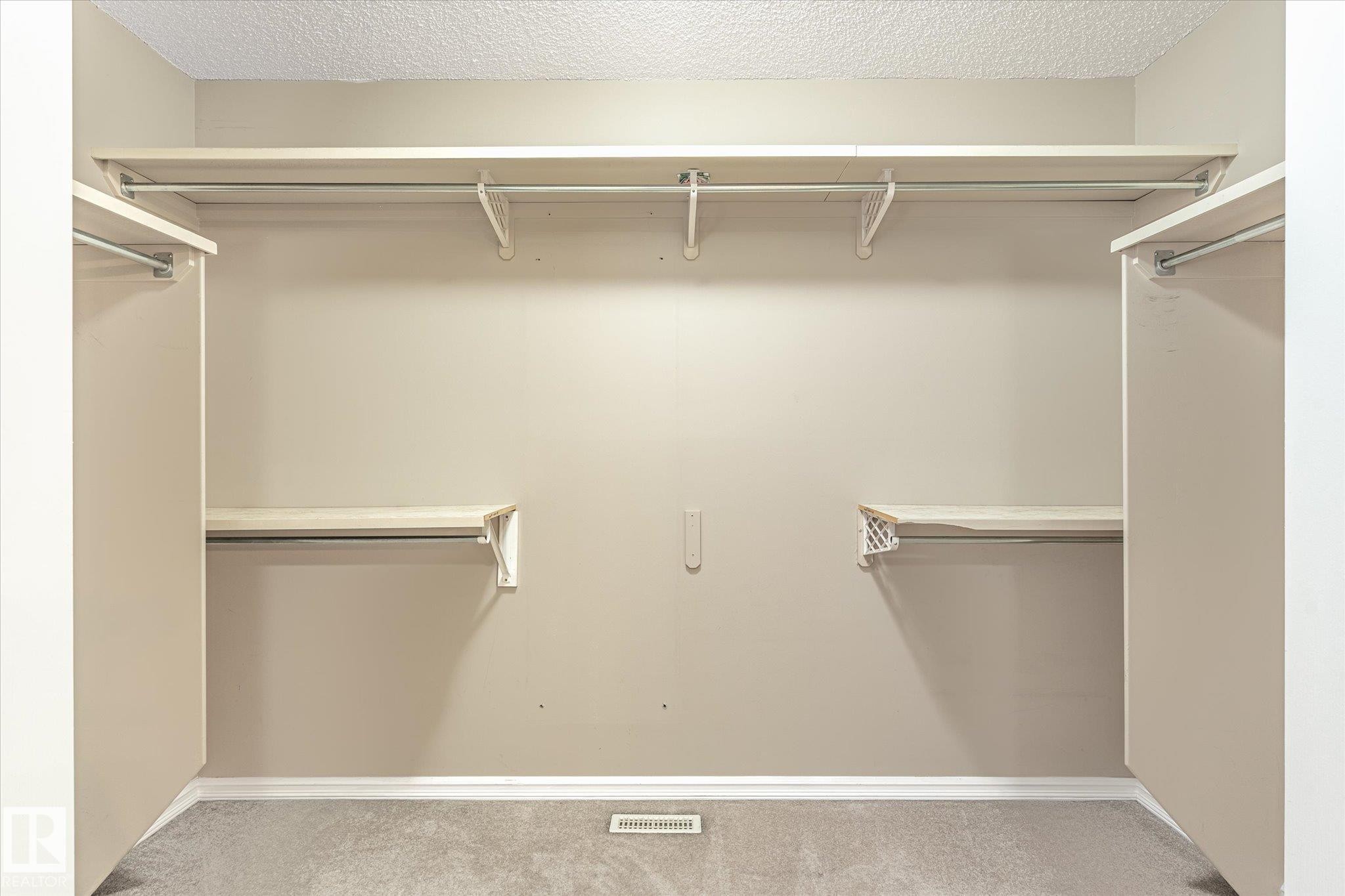 Walk-in closet with carpet flooring, multiple levels of built-in shelving, and hanging rods - 2550 Rabbit Hill Road Nw, Edmonton, AB