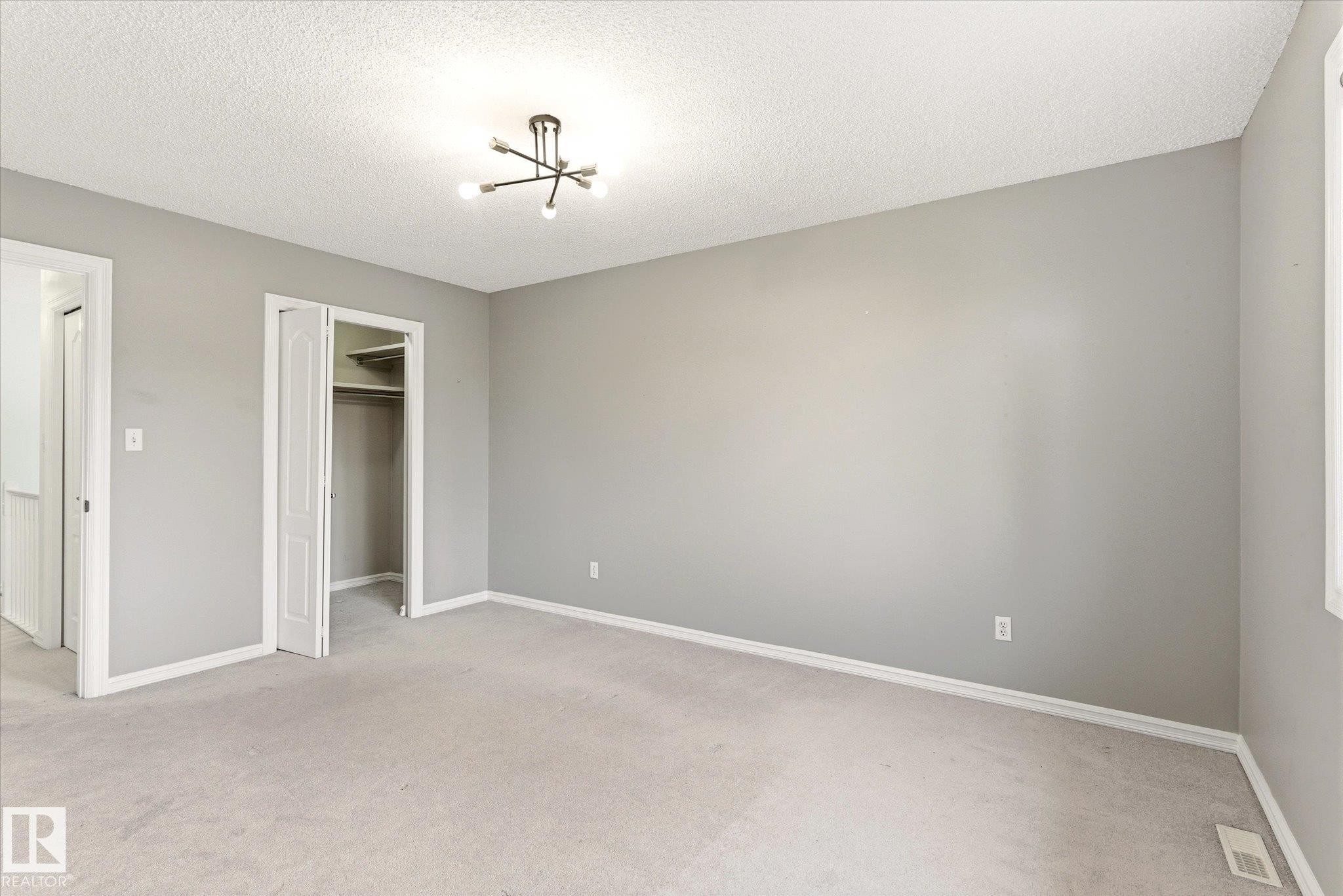 Gray painted walls with white trim, light gray carpeting, and a modern ceiling light fixture - 2550 Rabbit Hill Road Nw, Edmonton, AB