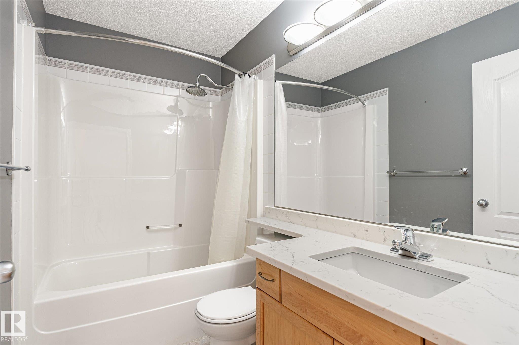 Bathroom featuring a vanity with an integrated sink, polished chrome faucet, wood-finish cabinetry, and a full-width mirror - 2550 Rabbit Hill Road Nw, Edmonton, AB