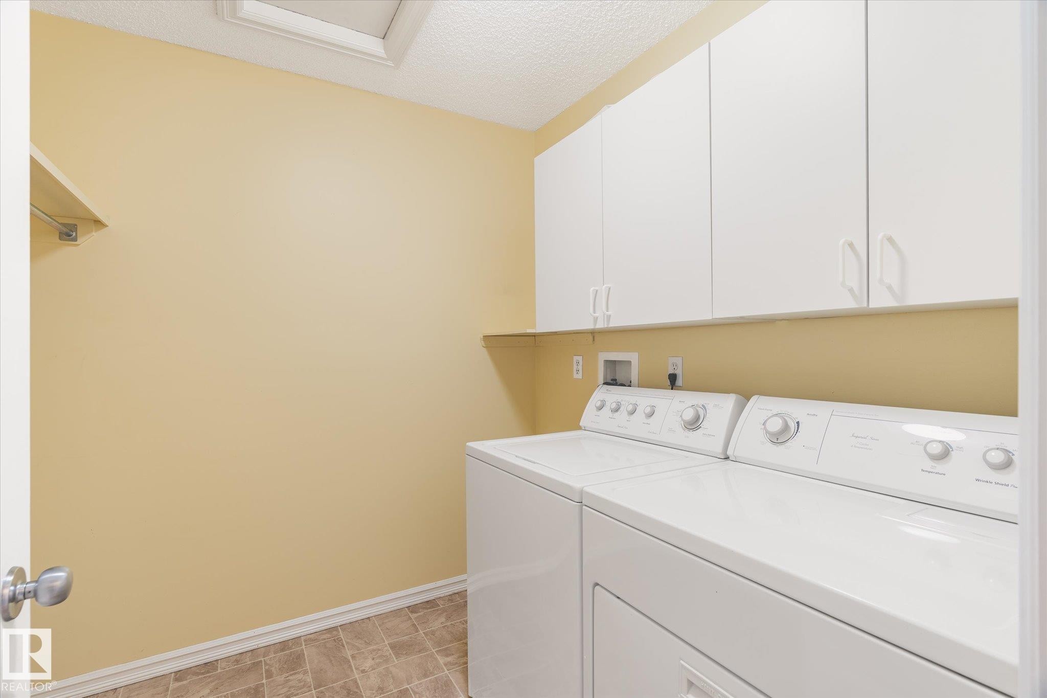 Laundry room featuring white cabinetry, a built-in shelf, and tile flooring - 2550 Rabbit Hill Road Nw, Edmonton, AB