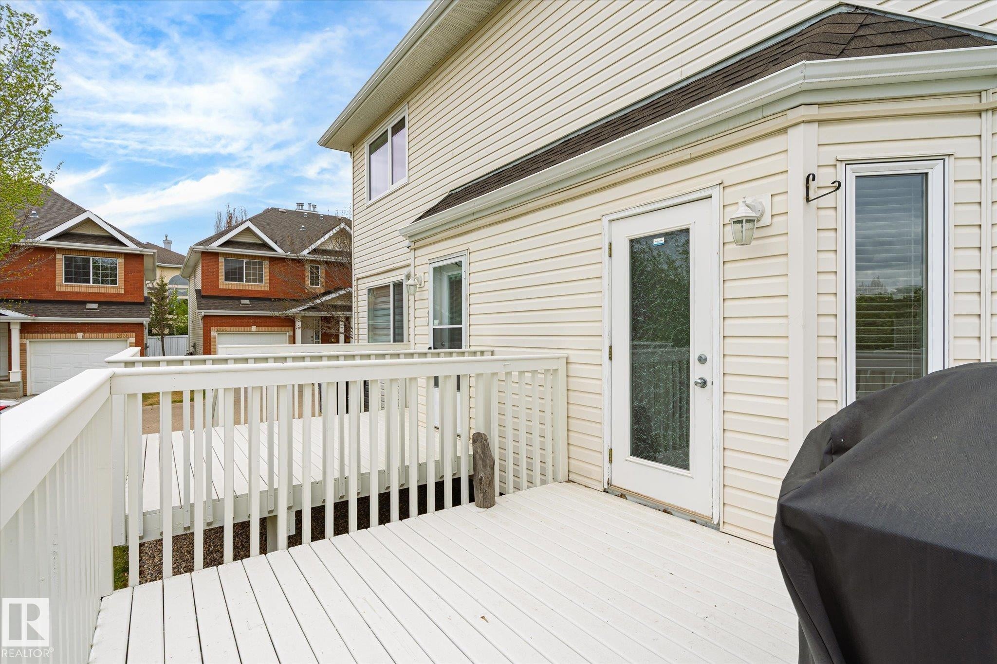 Expansive white wood deck with railing and direct access to the interior via a glass-paneled door - 2550 Rabbit Hill Road Nw, Edmonton, AB