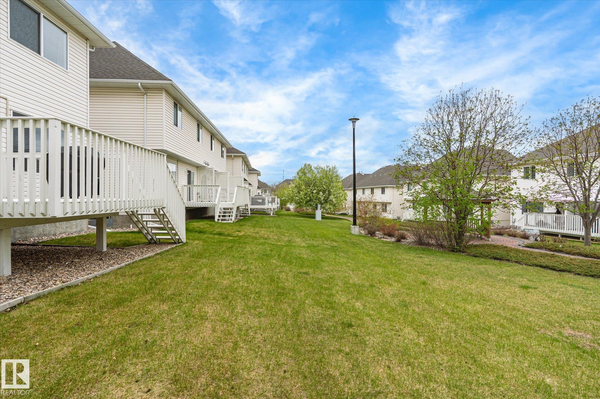 Elevated wood deck with stairs, expansive lawn, mature tree, and exterior siding - 2550 Rabbit Hill Road Nw, Edmonton, AB