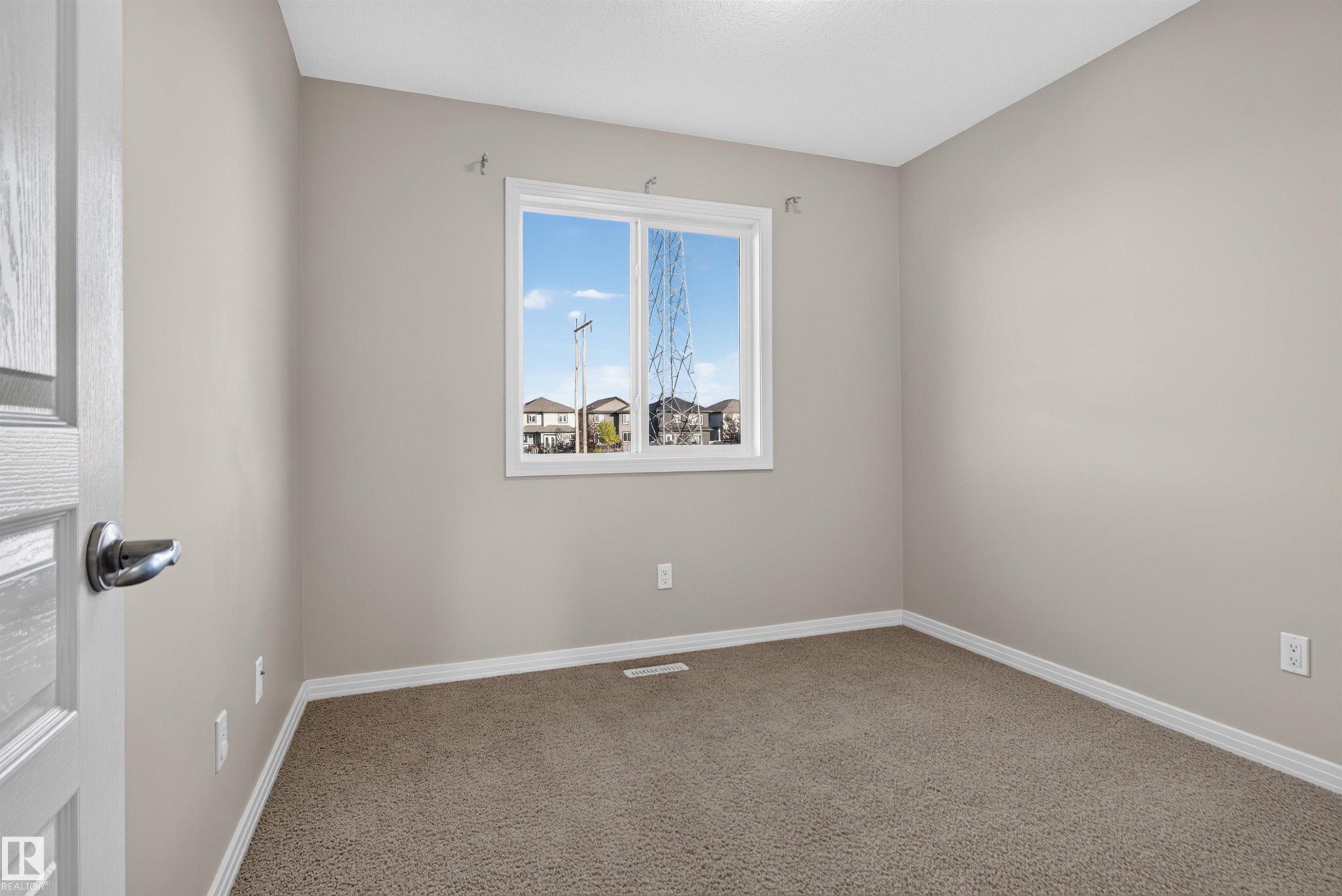 Neutral tone wall finishes, white trim, textured carpet flooring, and a single window - 2145 28 Street Nw, Edmonton, AB
