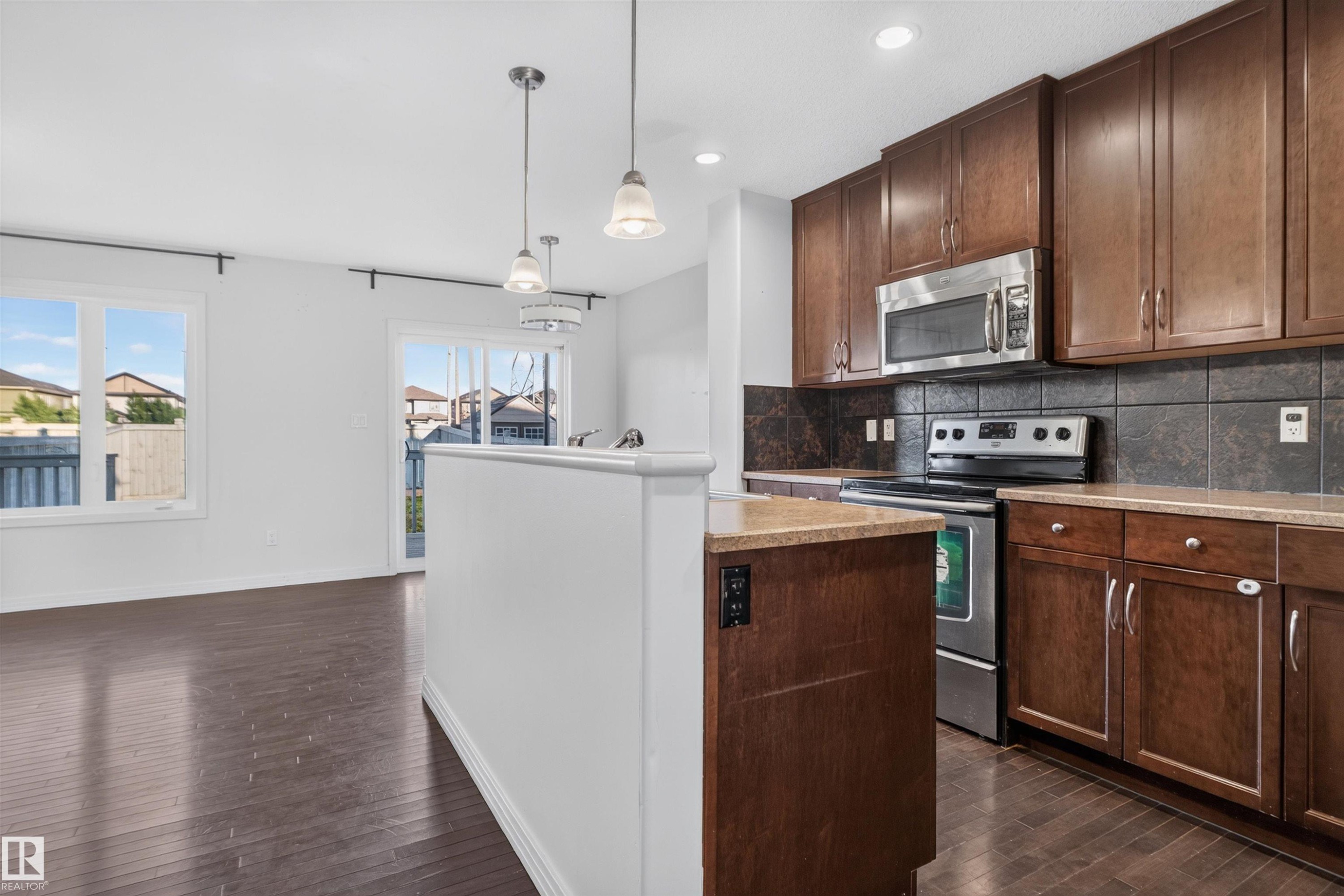 Rich wood-finish flooring complements white walls - 2145 28 Street Nw, Edmonton, AB