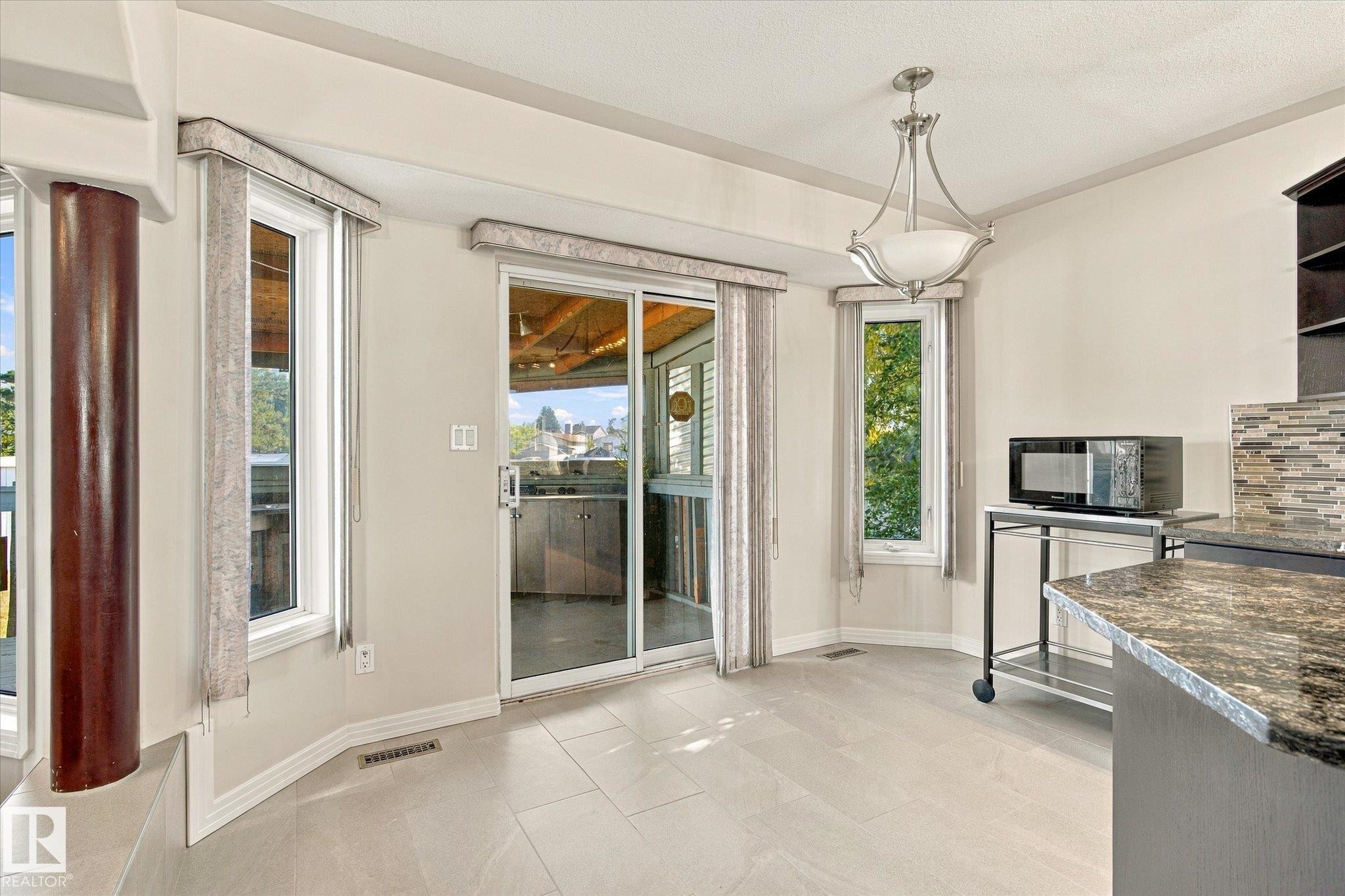 Tiled flooring, multiple windows, and a sliding glass door - 771 Johns Road Nw, Edmonton, AB