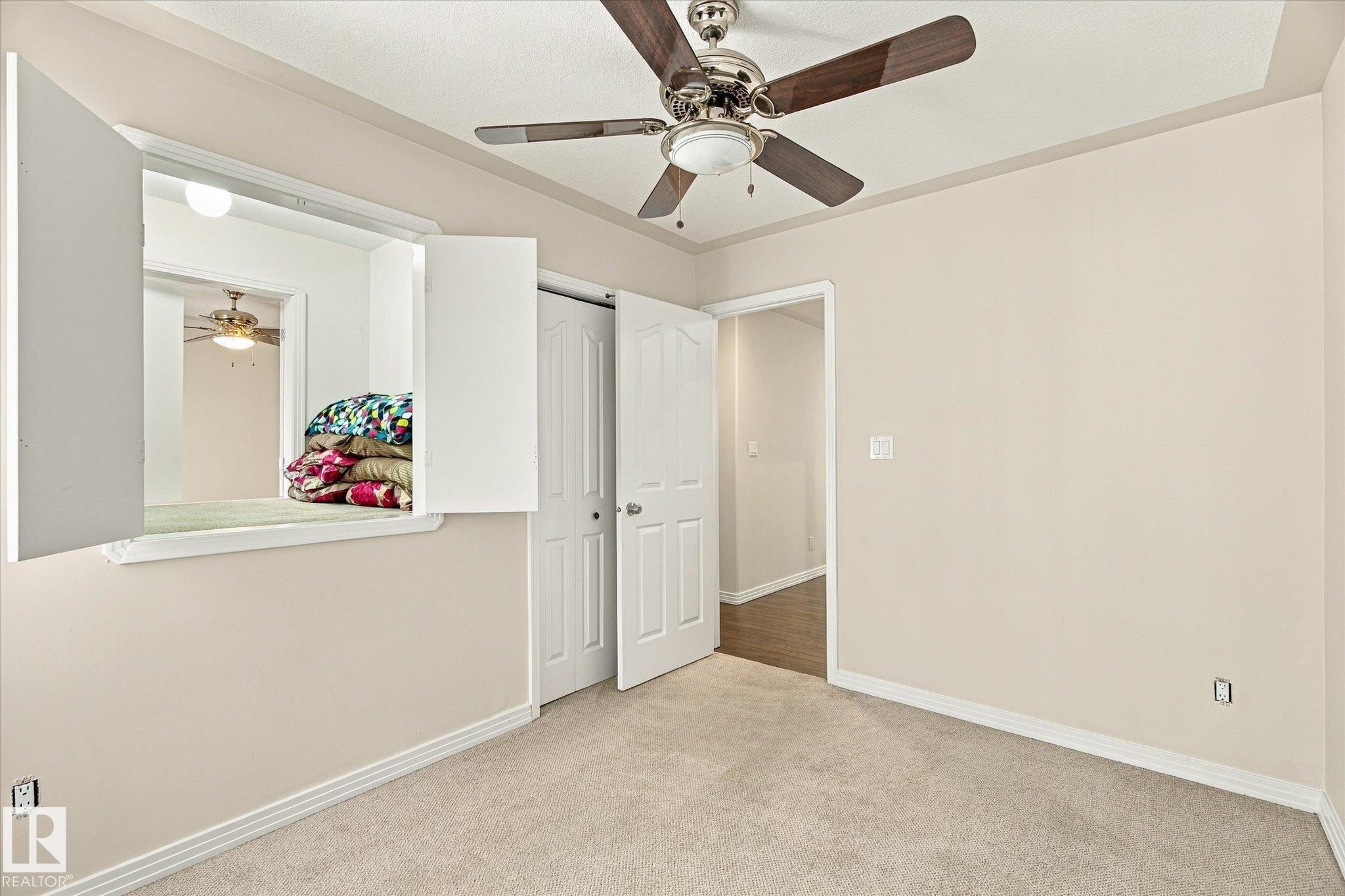 Ceiling fan with light fixture, neutral carpeting, white trim, and a white interior window with shutters - 771 Johns Road Nw, Edmonton, AB