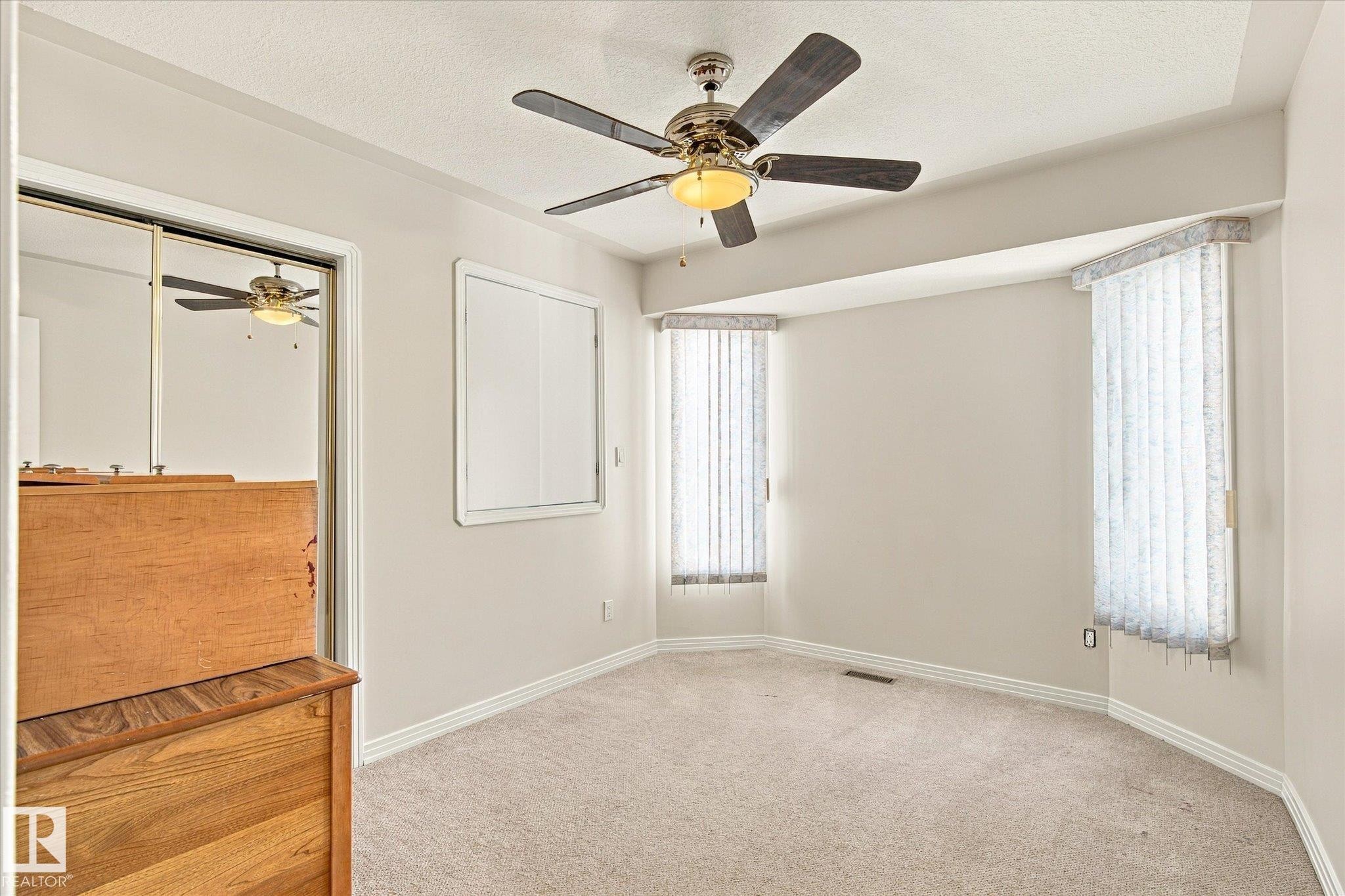 Recessed bay window, ceiling fan with light fixture, mirrored sliding closet doors, wall-to-wall carpeting, and white trim - 771 Johns Road Nw, Edmonton, AB
