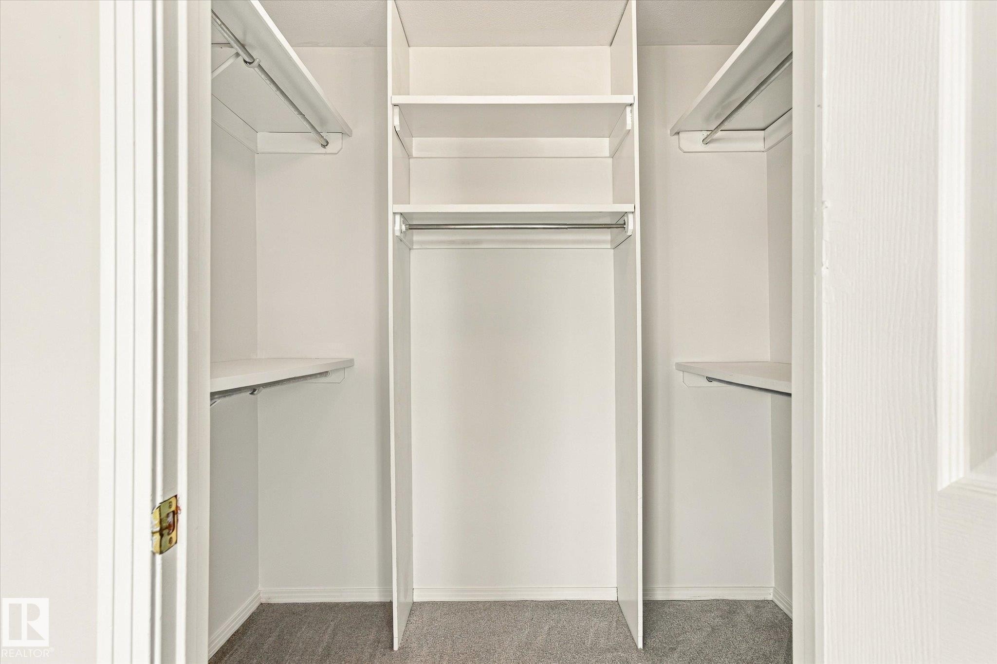 Built-in closet shelving, hanging rods, and gray carpet flooring - 771 Johns Road Nw, Edmonton, AB