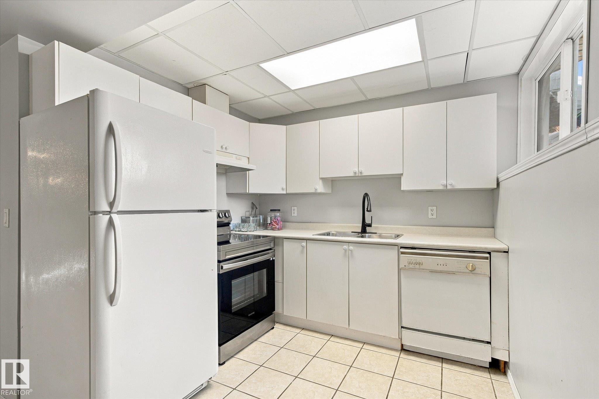 White cabinetry with matte black hardware, white appliances, stainless steel range, and tile flooring - 771 Johns Road Nw, Edmonton, AB