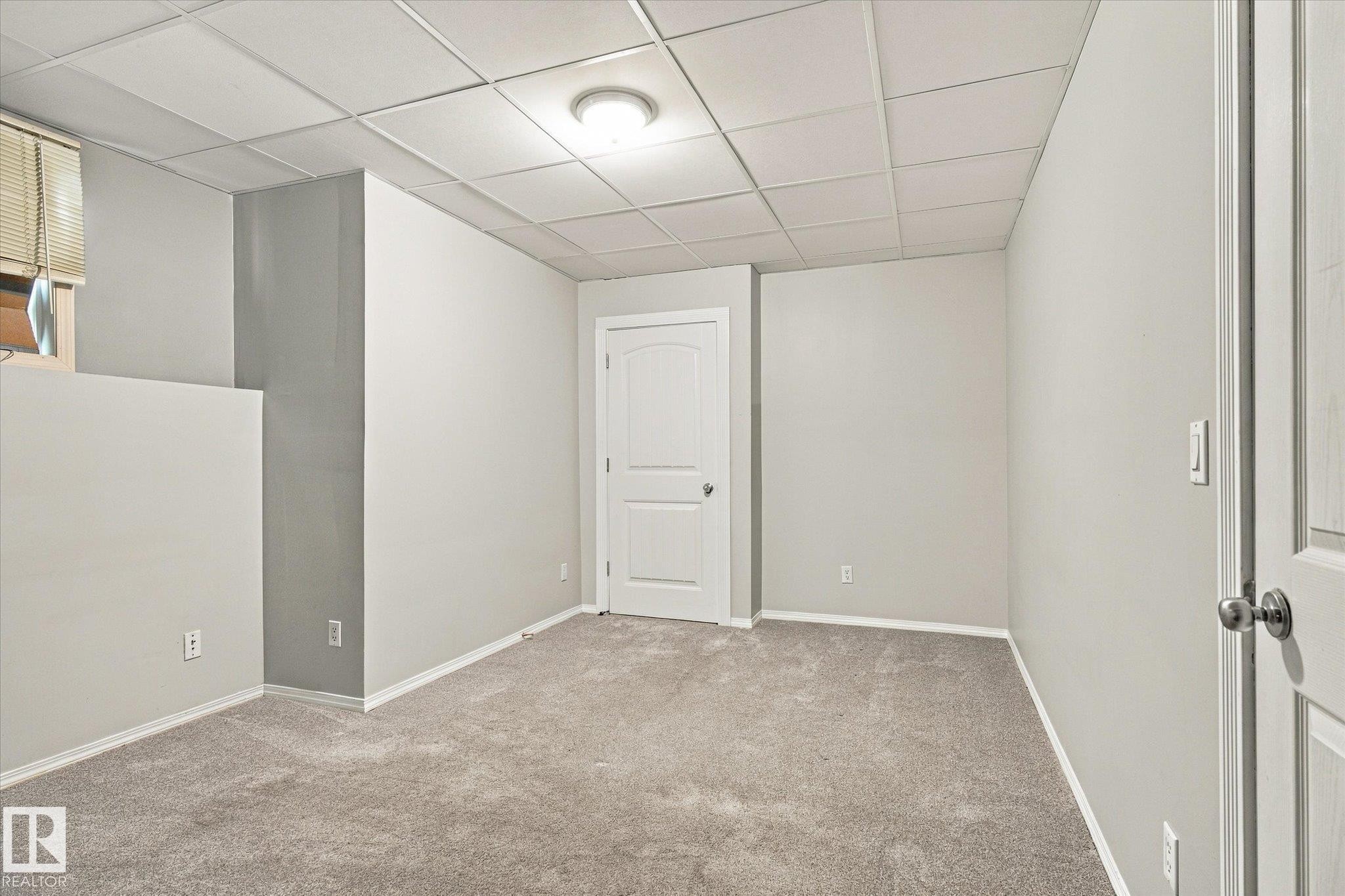 Plush gray carpeting, white painted walls, white paneled interior doors, and a drop ceiling with recessed lighting - 771 Johns Road Nw, Edmonton, AB