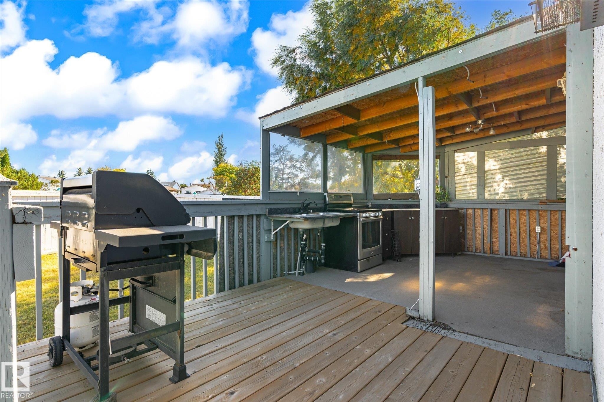 Outdoor deck featuring a built-in outdoor kitchen with a sink, cabinetry, and an under-counter appliance - 771 Johns Road Nw, Edmonton, AB