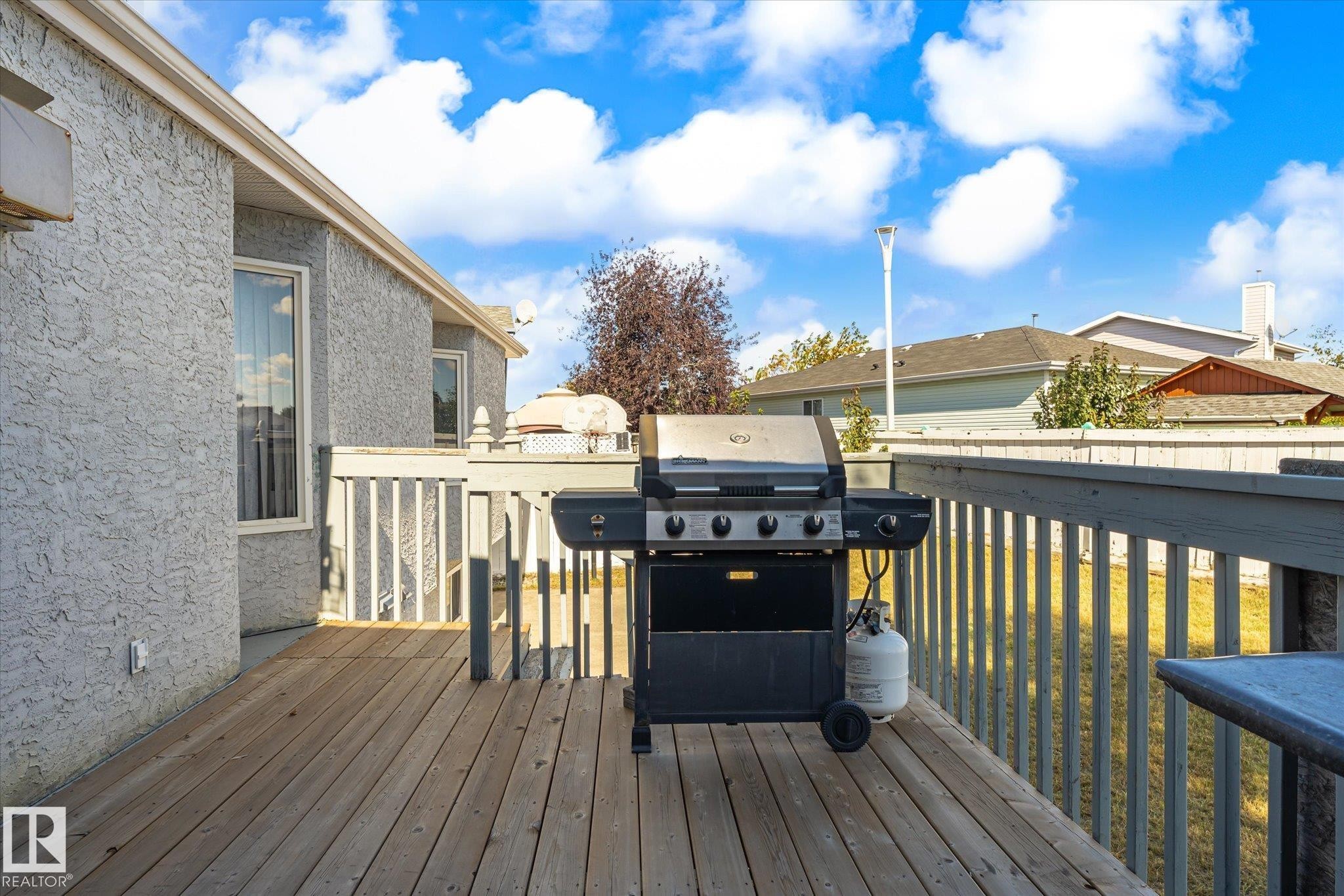 Wood-finish deck with a painted wood railing and textured exterior siding - 771 Johns Road Nw, Edmonton, AB