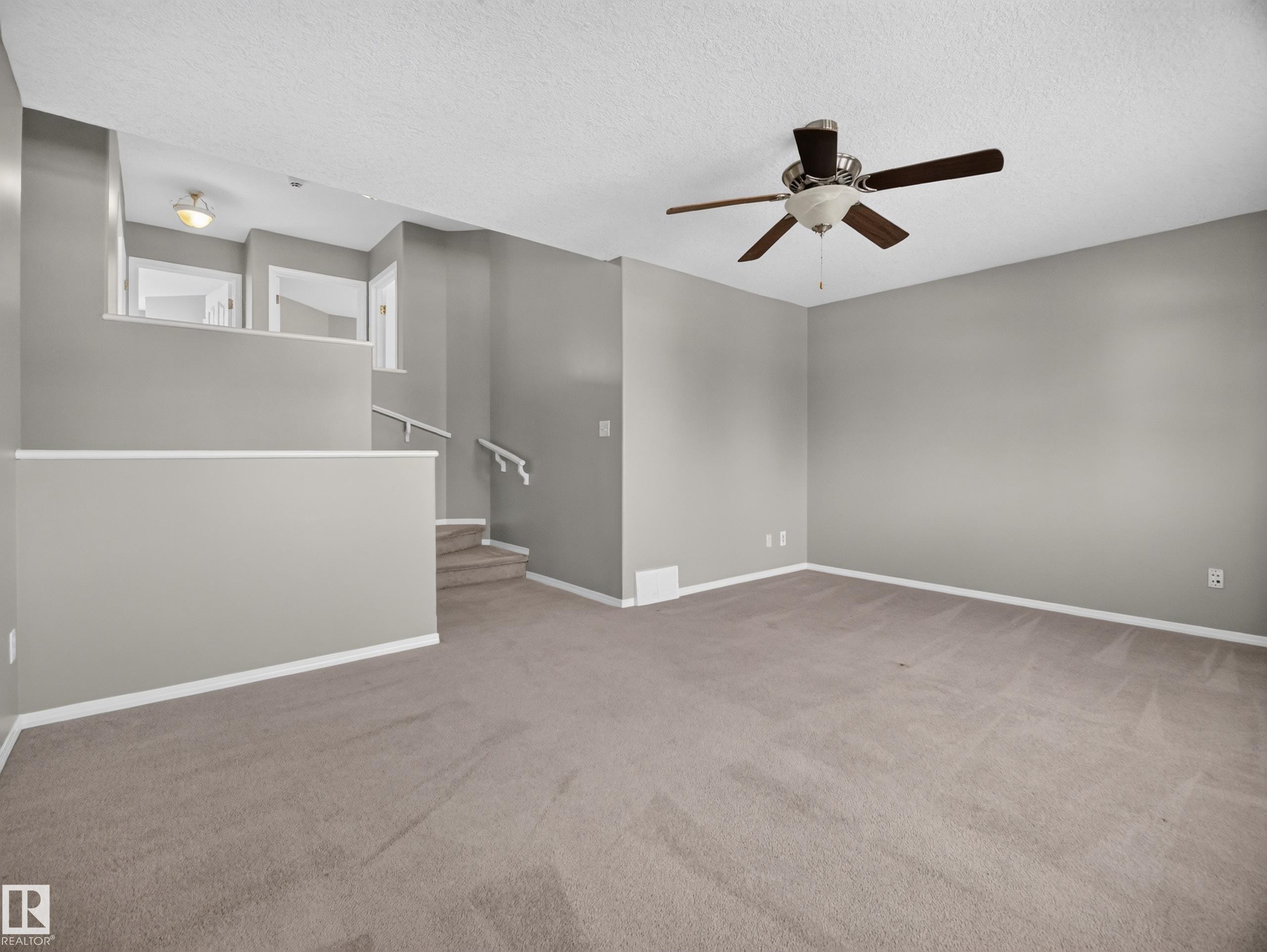 Spacious room with neutral carpeting and light gray wall paint - 14 Wells Court, Leduc, AB