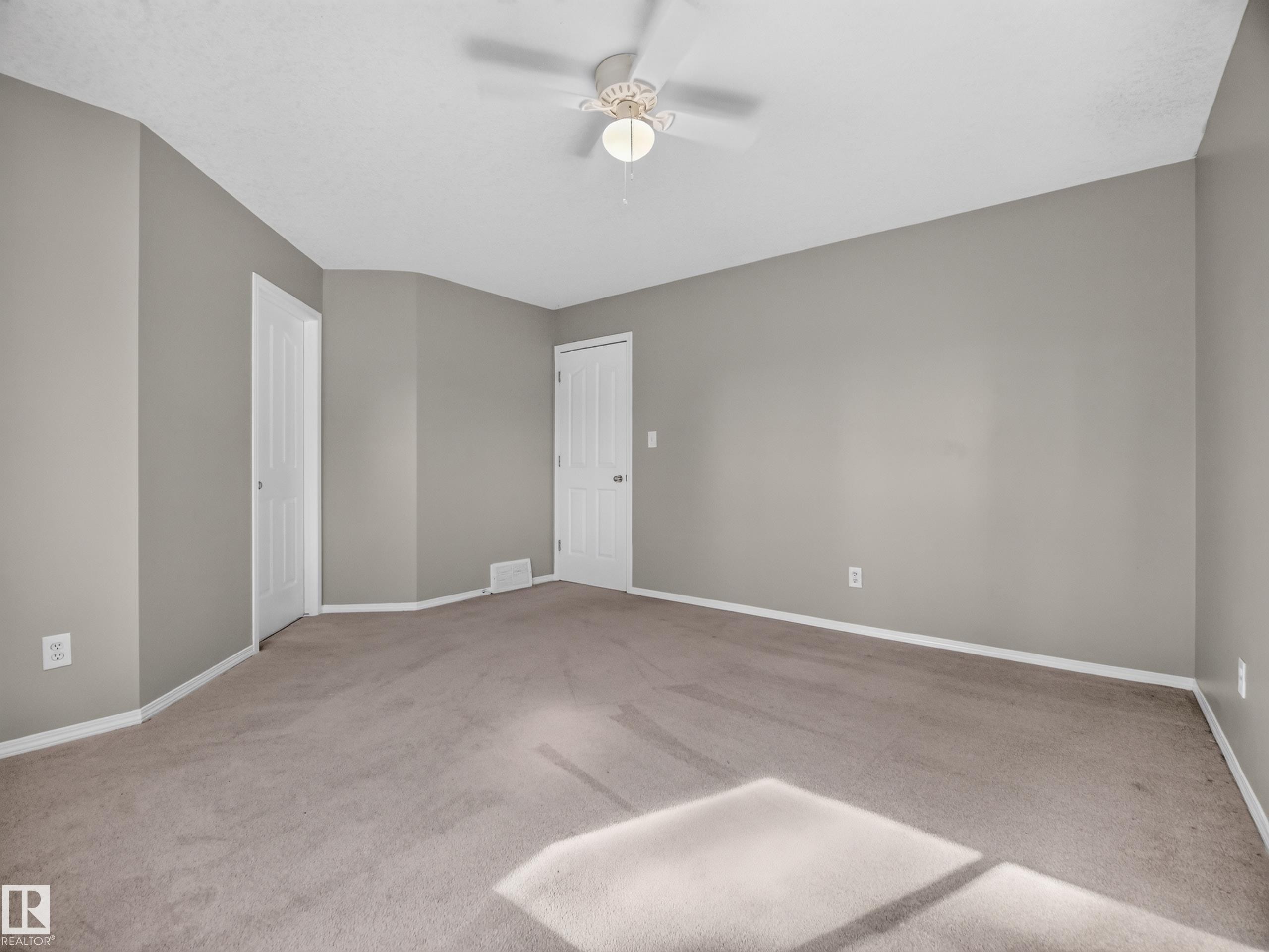 Spacious room with neutral wall tones and carpeted flooring - 14 Wells Court, Leduc, AB