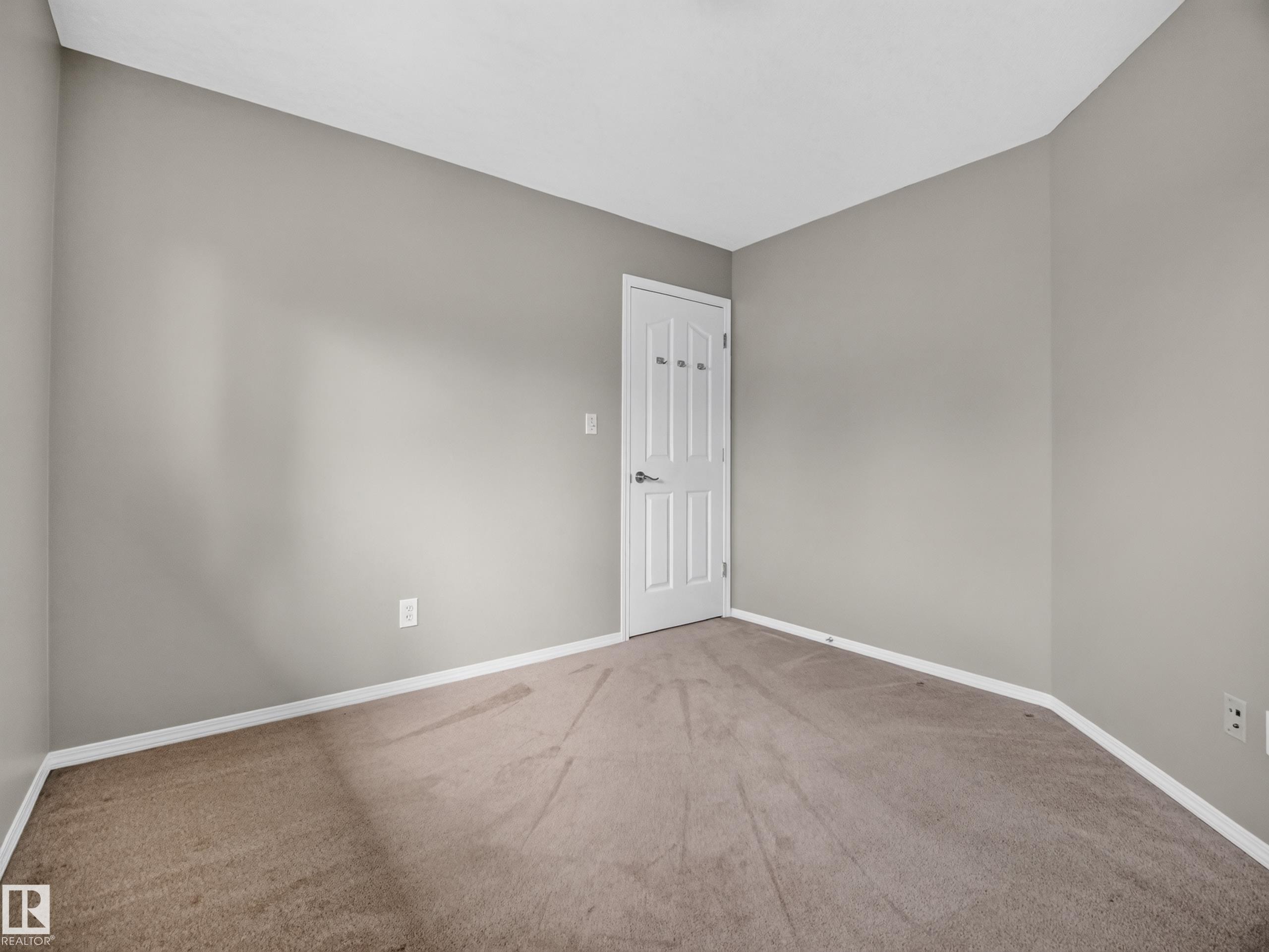 Neutral wall paint, plush carpet flooring, white trim, and a white interior door - 14 Wells Court, Leduc, AB