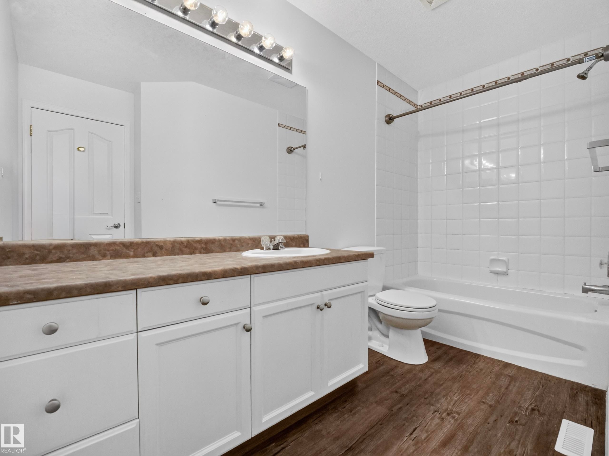 Bathroom featuring a white vanity with brown countertop, integrated sink, and white cabinetry - 14 Wells Court, Leduc, AB
