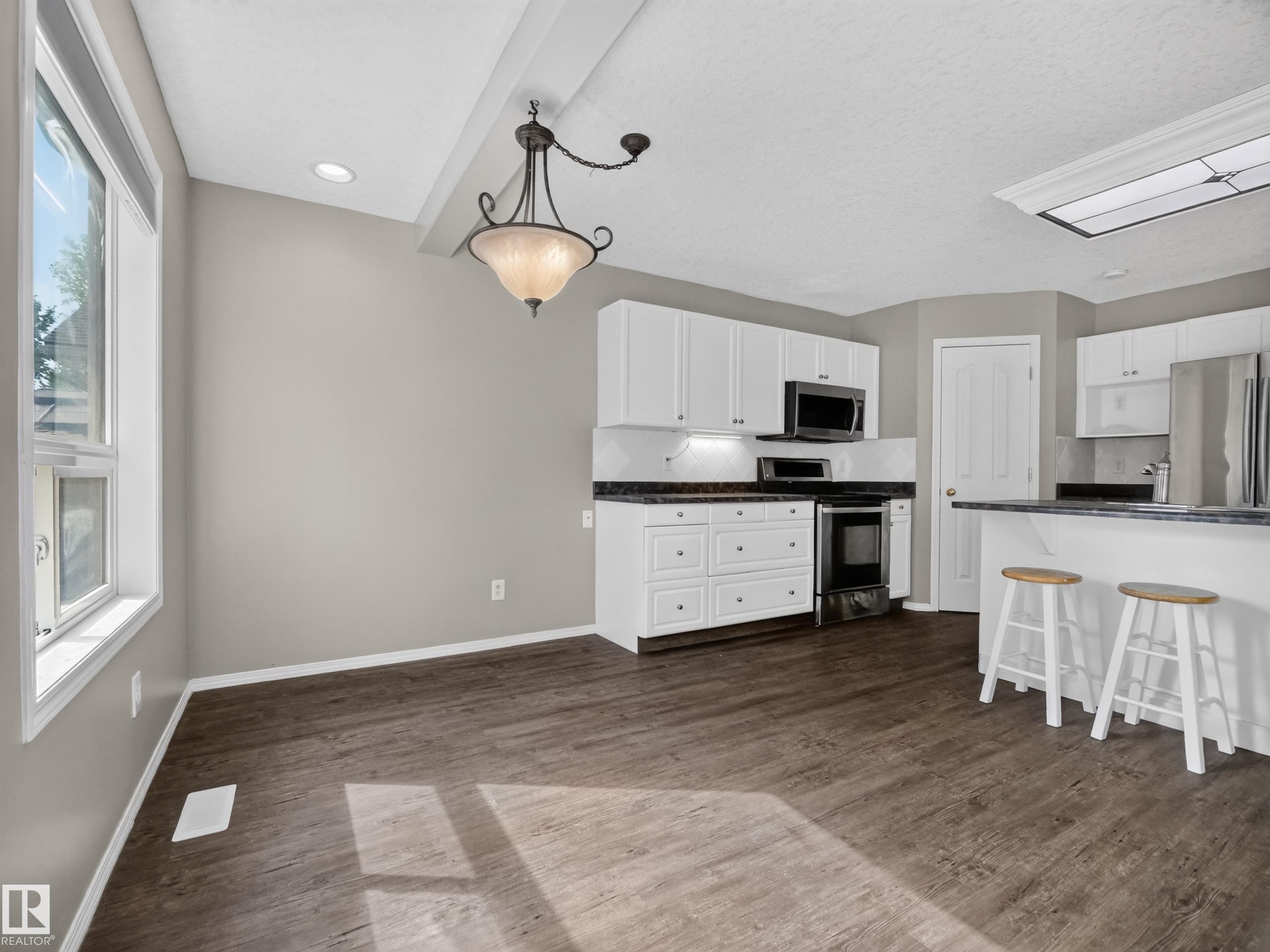 Spacious dining area with wood-finish flooring, recessed lighting, and a decorative ceiling fixture - 14 Wells Court, Leduc, AB