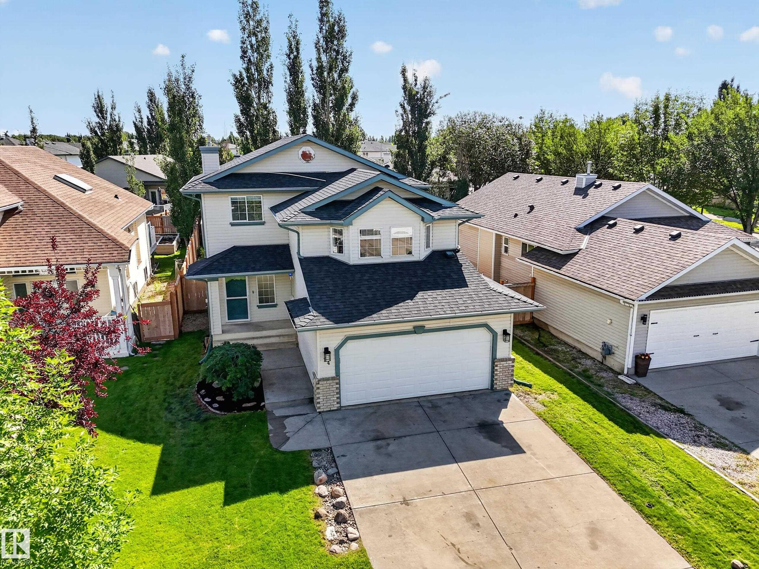 Two-story residence featuring a two-car garage, concrete driveway, and established landscaping - 14 Wells Court, Leduc, AB