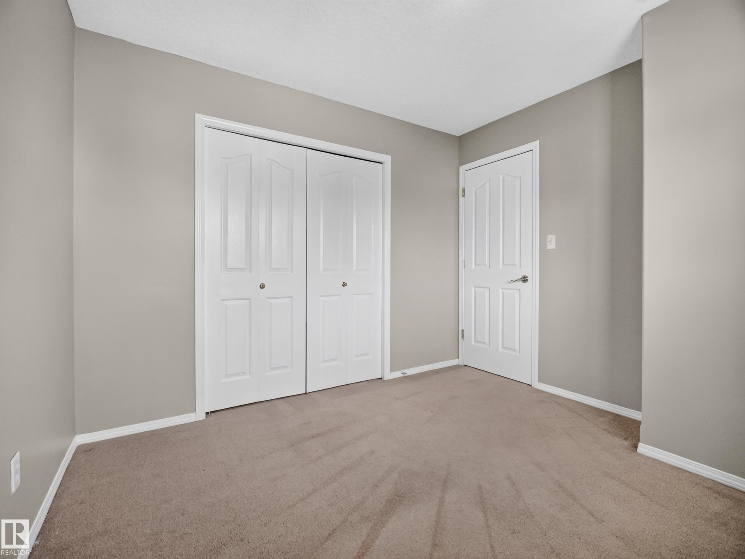 Neutral tone wall paint, white trim, paneled interior doors, and carpet flooring - 14 Wells Court, Leduc, AB