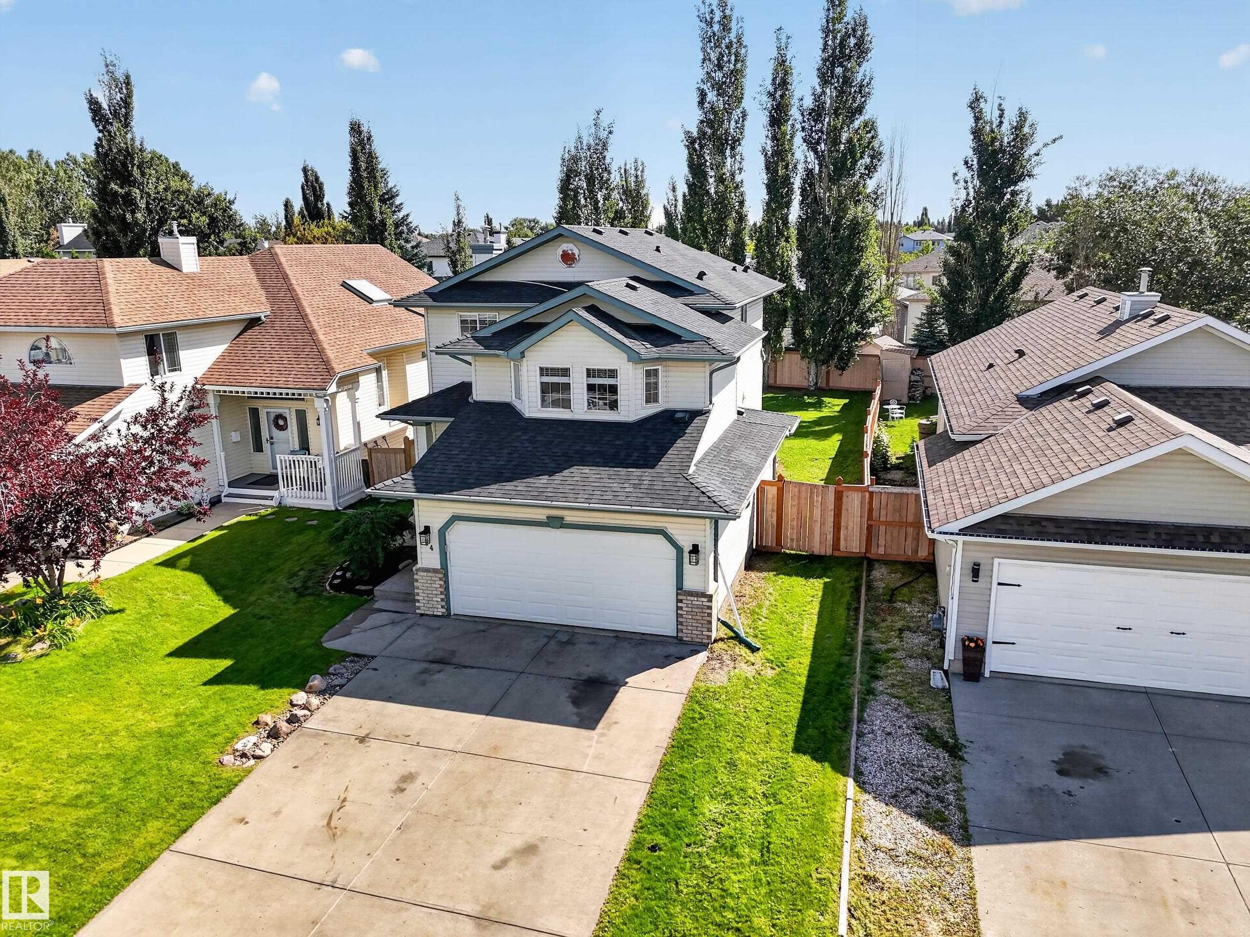 Two-story home with a two-car garage, concrete driveway, and a fenced backyard with a manicured lawn - 14 Wells Court, Leduc, AB