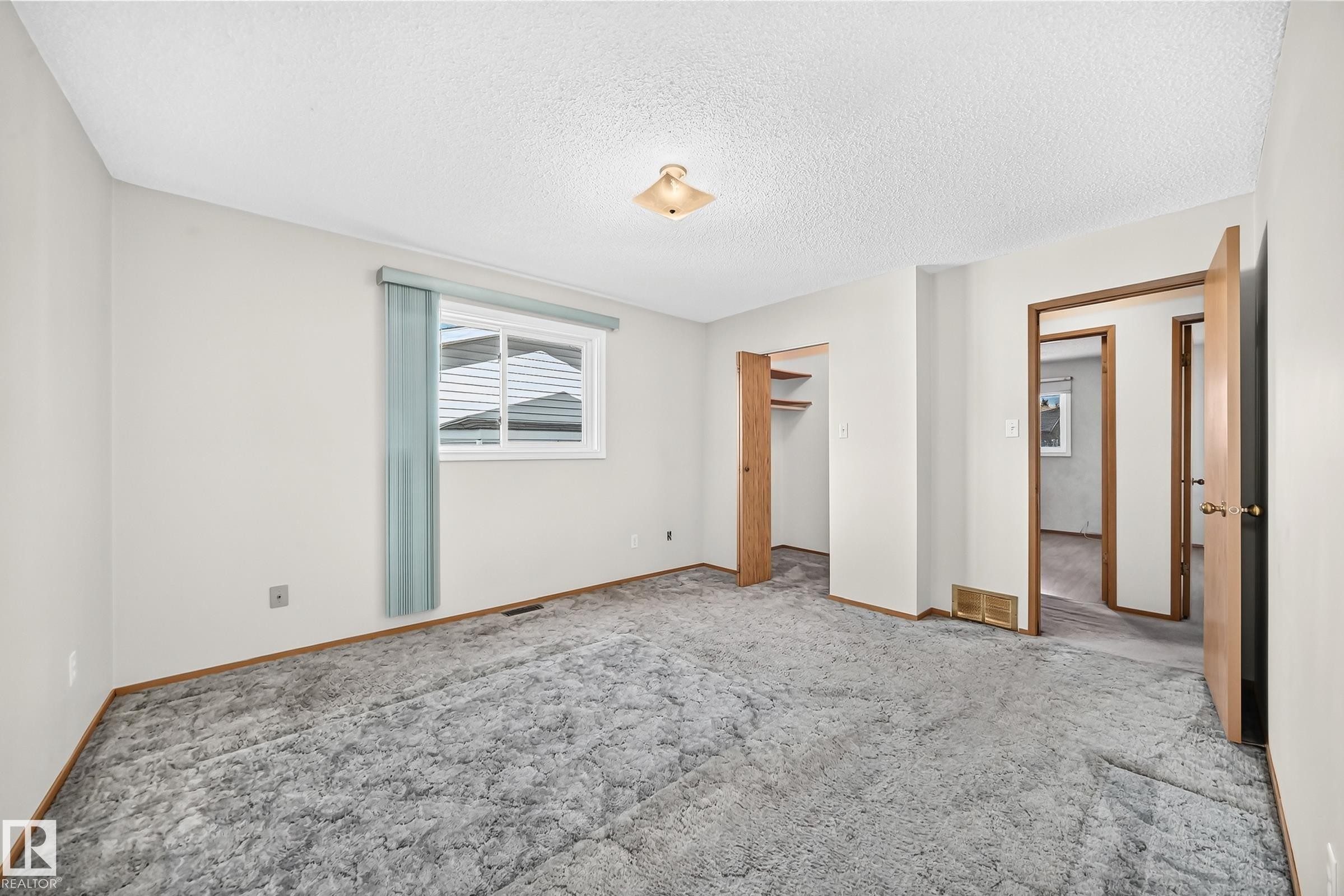 Carpeted flooring with painted walls, a built-in closet, and a window with blinds - 14519 32 Street Nw, Edmonton, AB