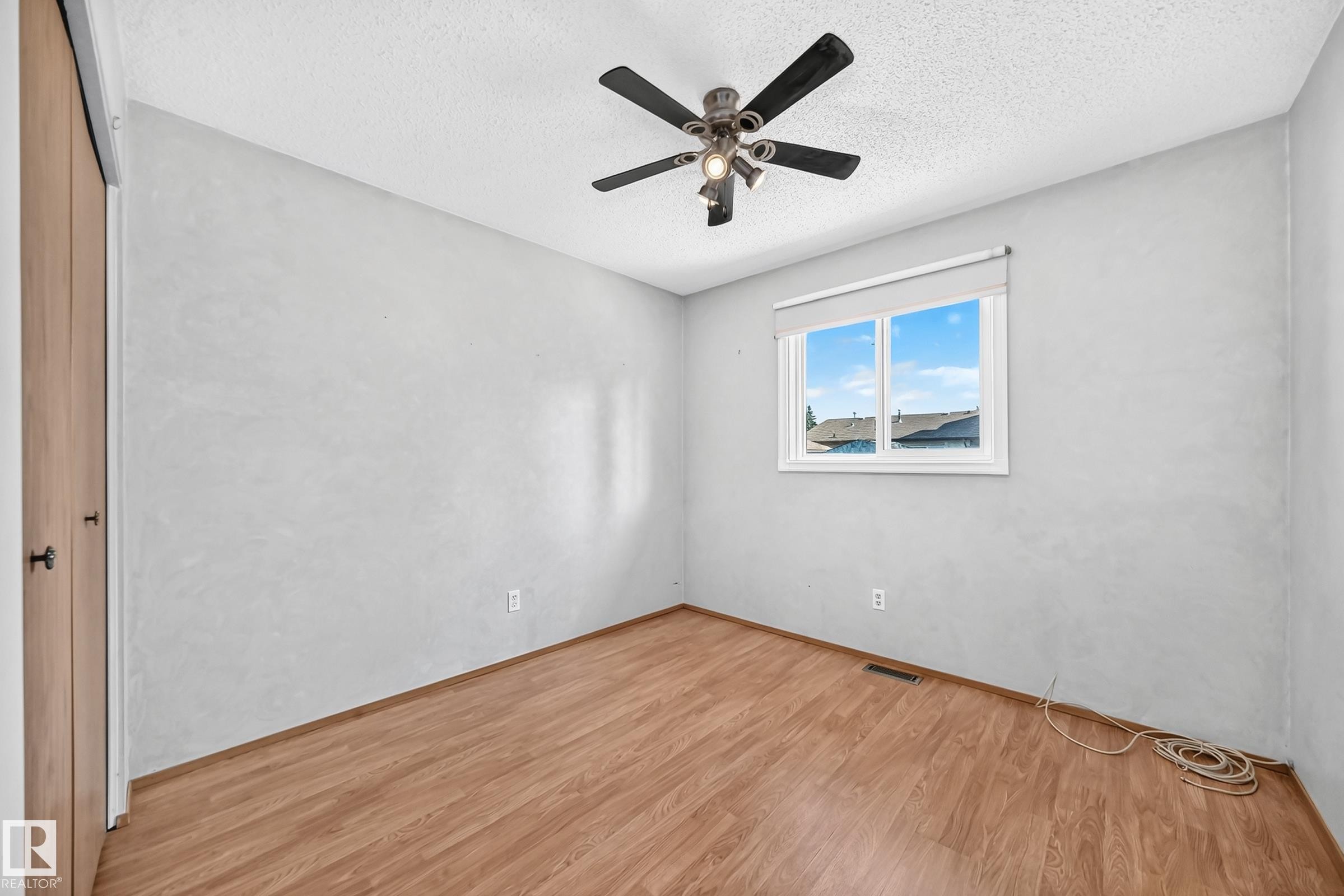 Wood-finish flooring, ceiling fan with integrated lighting, and a window with blinds - 14519 32 Street Nw, Edmonton, AB