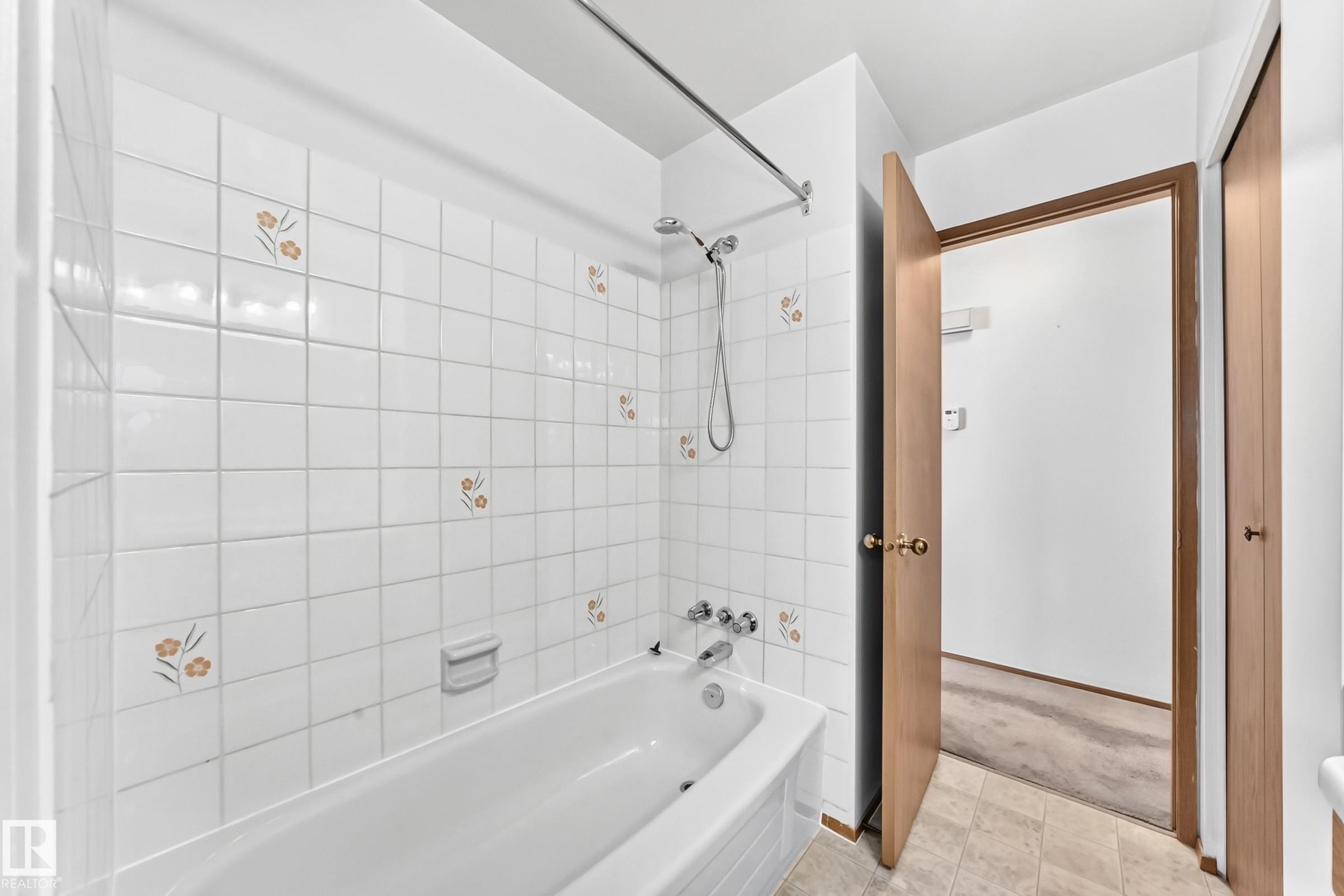 White subway tile surround with floral accents and a built-in bathtub - 14519 32 Street Nw, Edmonton, AB