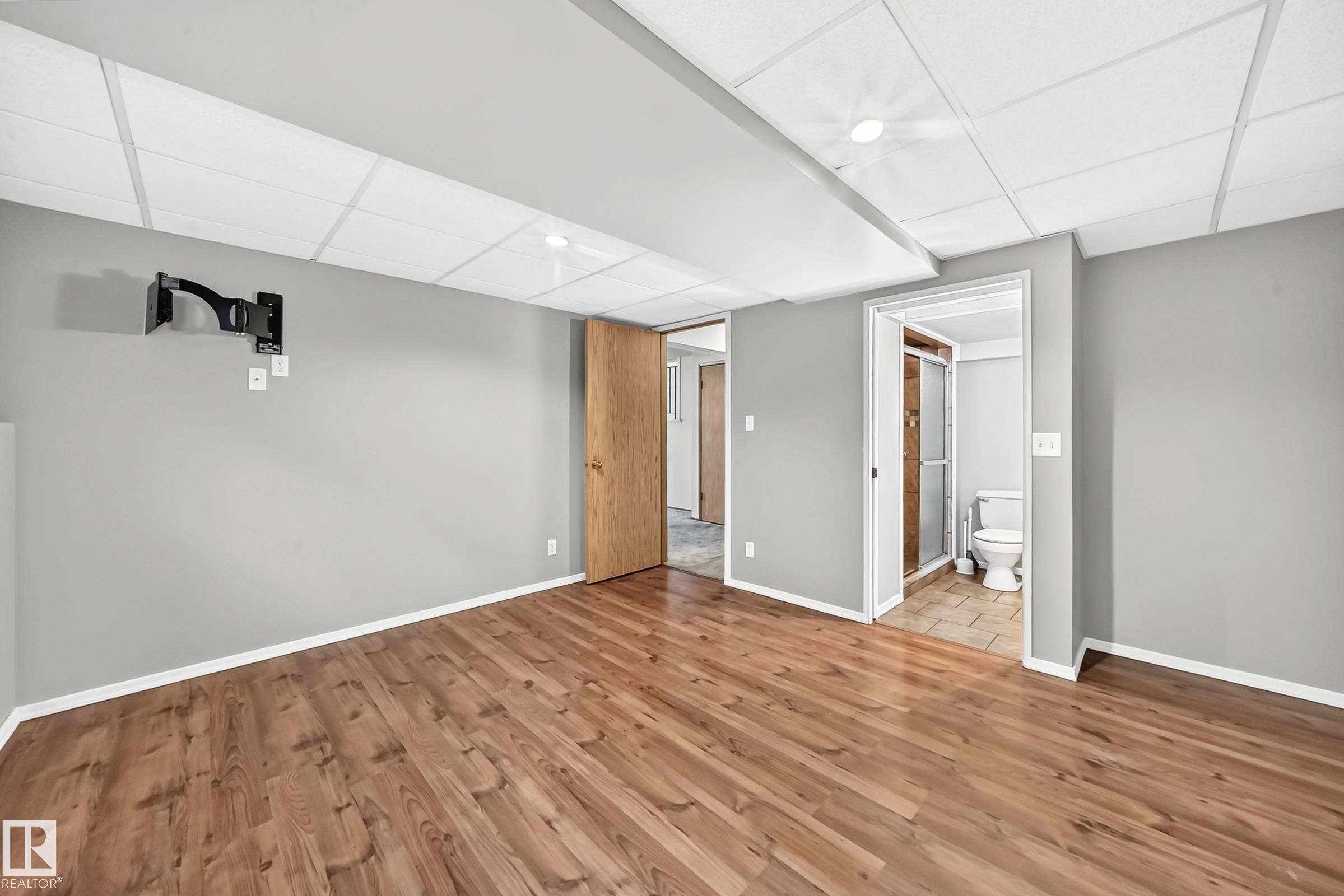 Finished basement featuring wood-finish flooring, recessed lighting throughout, and clean gray walls - 14519 32 Street Nw, Edmonton, AB