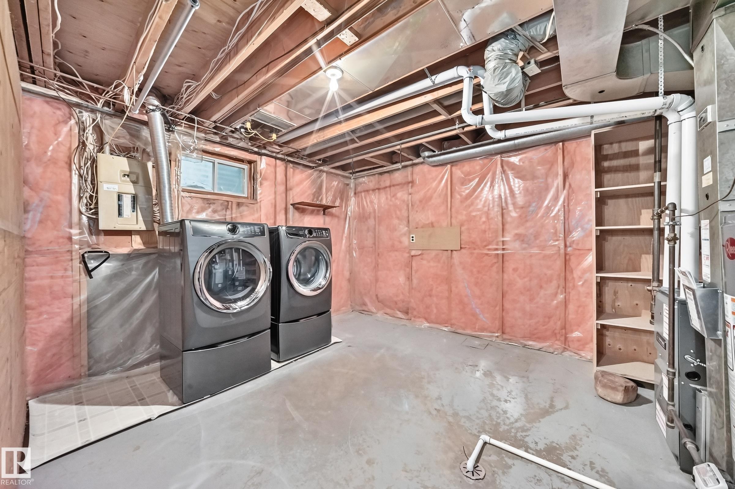 Laundry area featuring a window, built-in shelving, exposed ceiling joists, and concrete flooring - 14519 32 Street Nw, Edmonton, AB