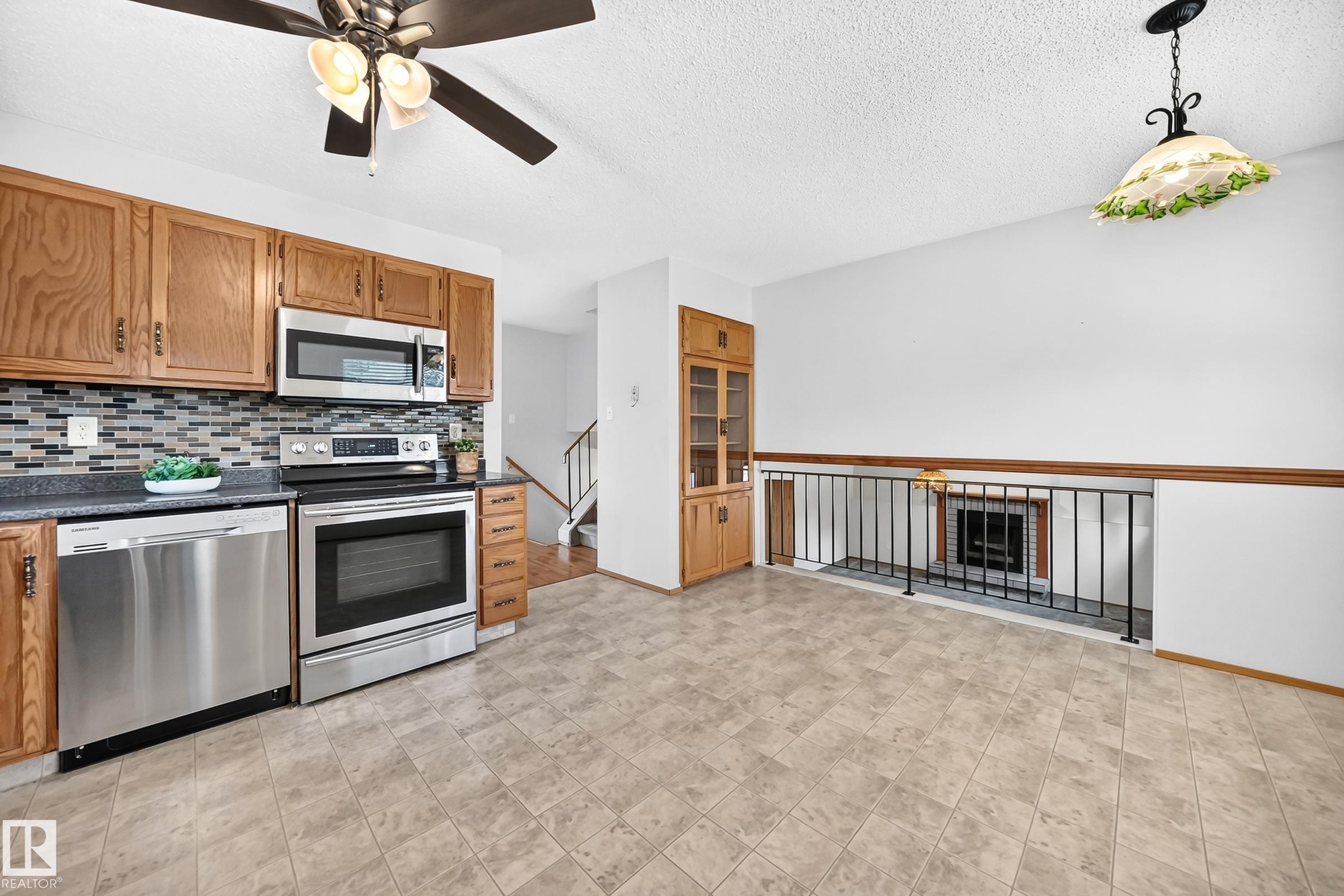 Kitchen featuring stainless steel appliances, wood cabinetry, a tiled backsplash, and a ceiling fan with integrated lighting - 14519 32 Street Nw, Edmonton, AB